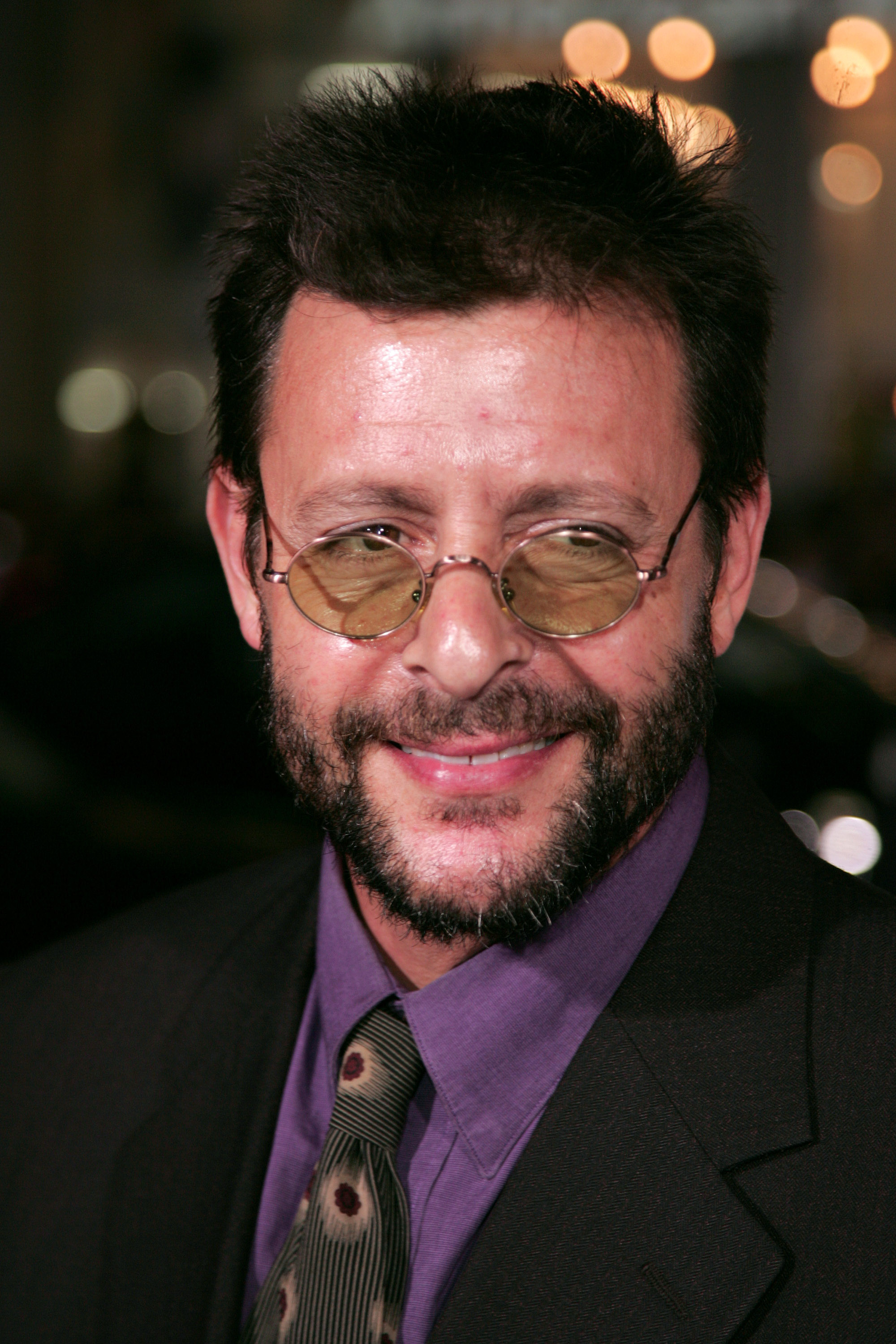Wearing small round tinted glasses, a full beard, and a purple collared shirt with a patterned tie, the actor smiled warmly upon arriving at Grauman's Chinese Theatre for the Hollywood premiere of "Jackass: Number Two." | Source: Getty Images