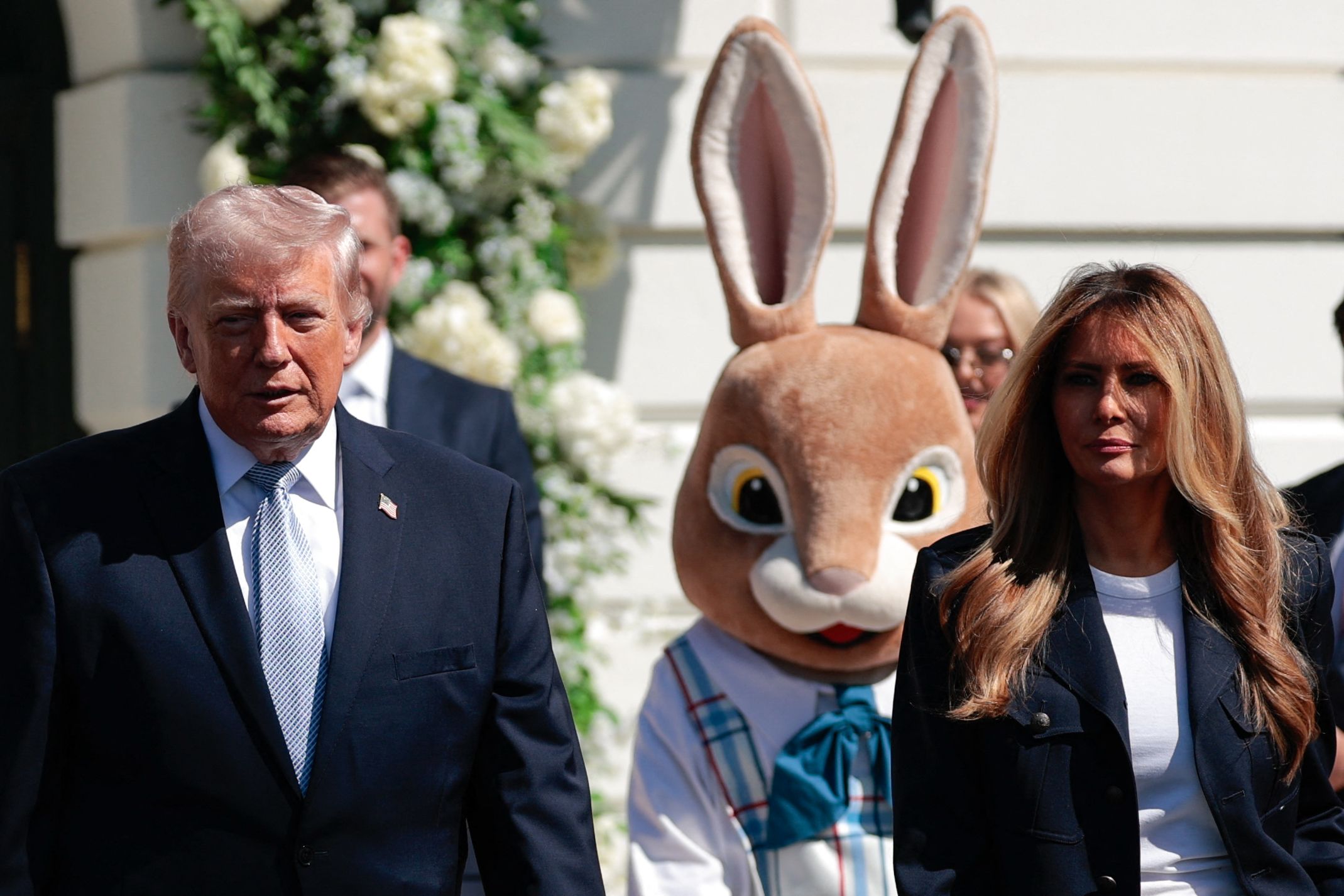 Donald and Melania Trump walk past the Easter Bunny on the South Lawn during the 2026 White House Easter Egg Roll, with both dressed in coordinated formal looks for the annual event.