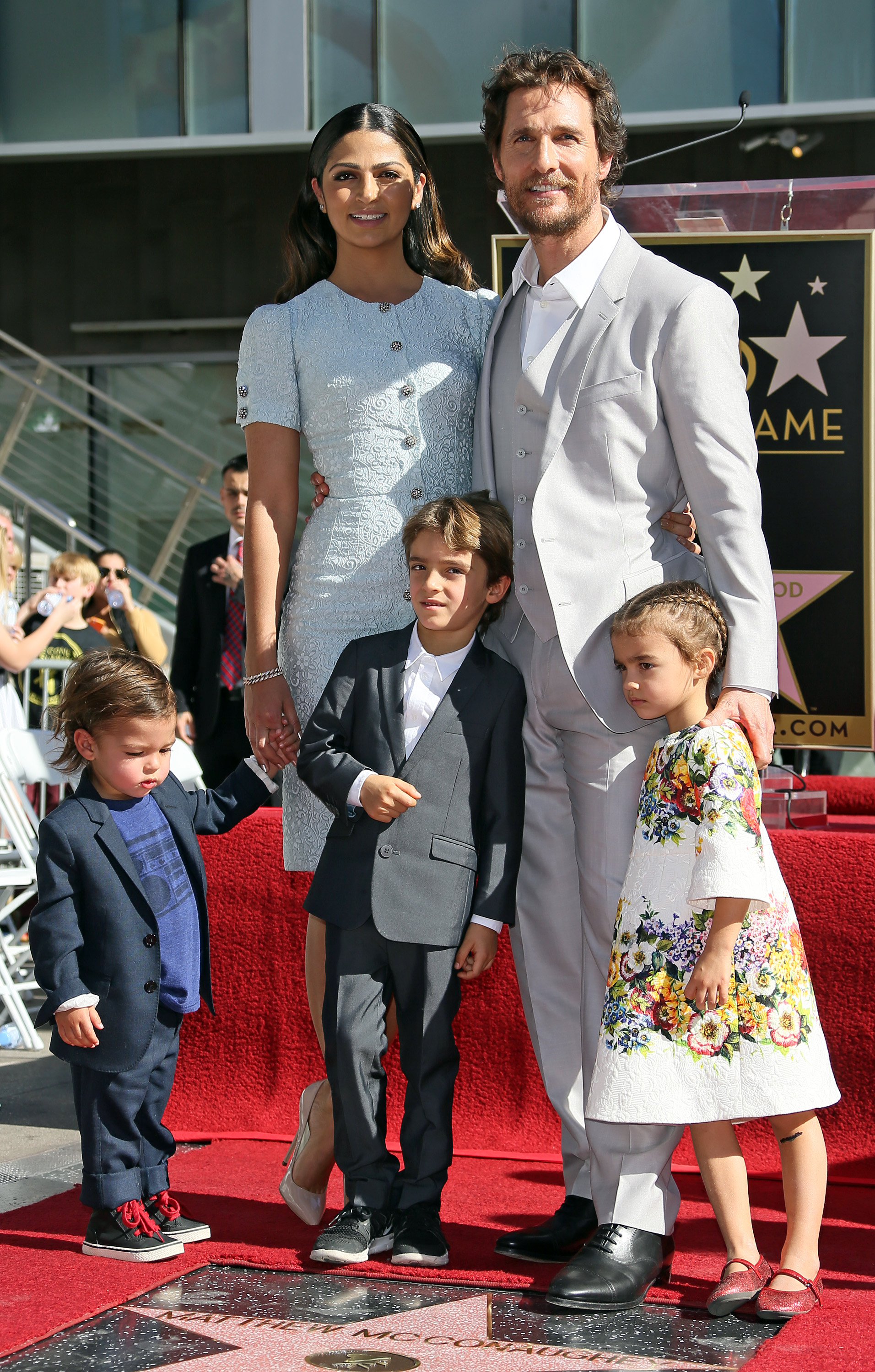 Levi McConaughey and Livingston McConaughey stand in small suits beside Camila Alves. Vida stands near Matthew in a patterned dress, looking to the side. The children are positioned in front as the family stands together on the red carpet.