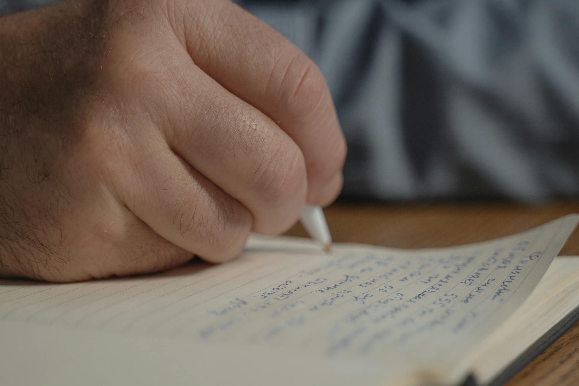 Close-up of a man writing in a diary | Source: Pexels