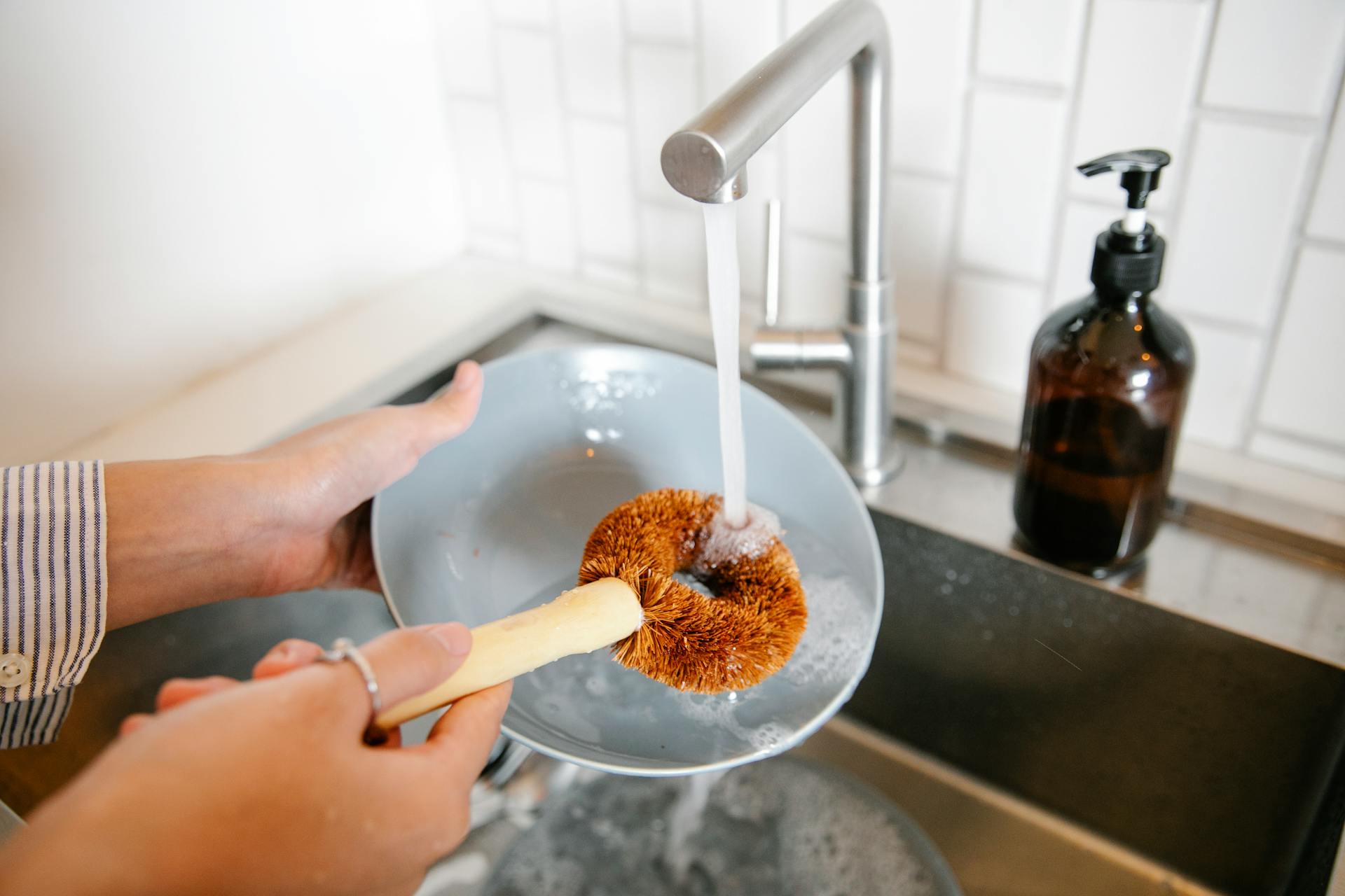 A closeup of a woman washing dishes in the kitchen | Source: Pexels