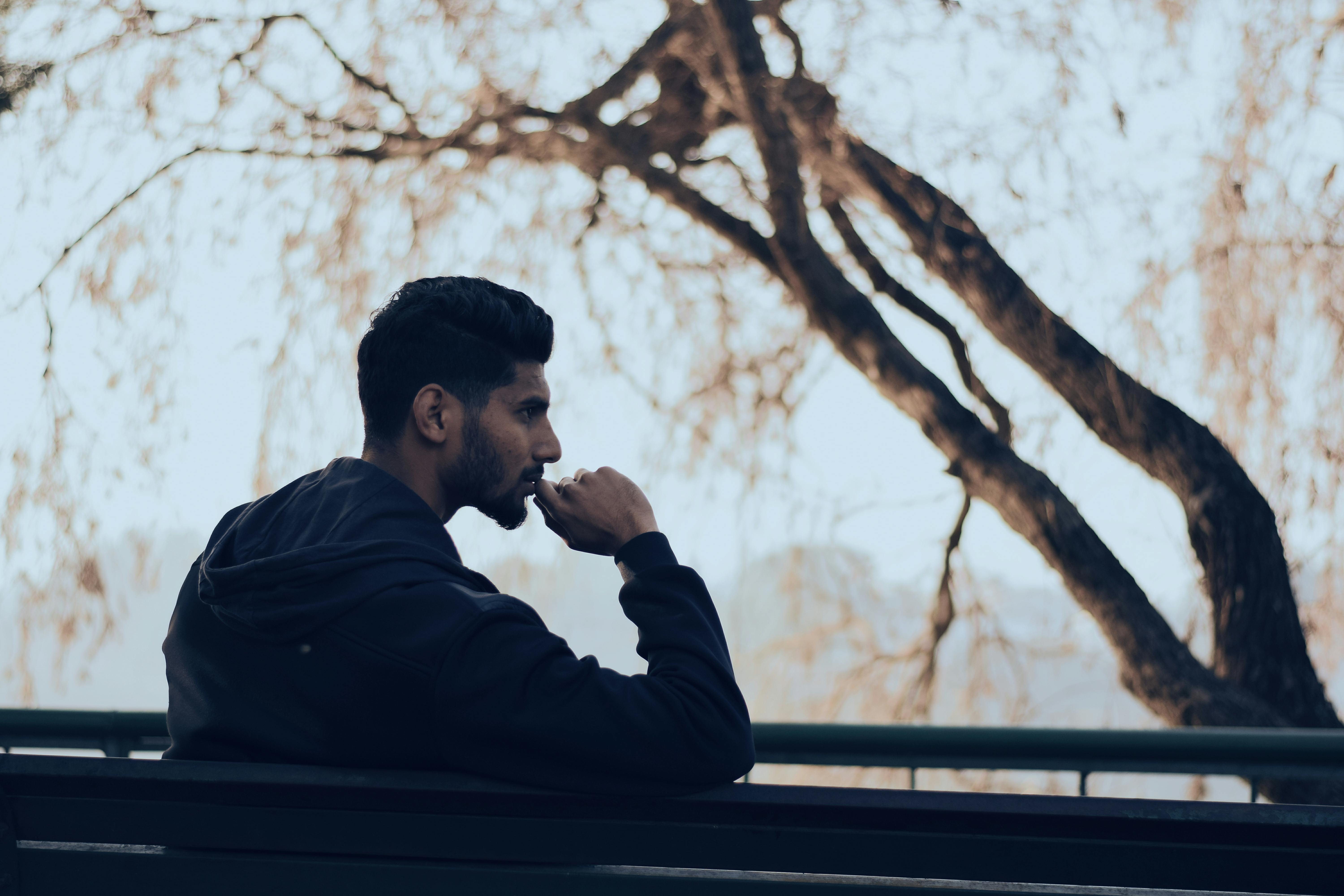 A man in sitting on a bench near trees | Source: Pexels