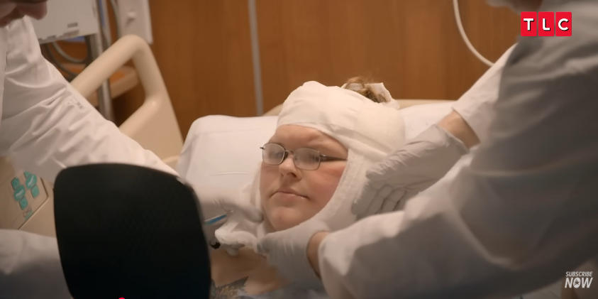 Tammy grips a mirror, eyes wide as her new face is revealed, from a video posted on June 11, 2025 | Source: YouTube/AccessHollywood
