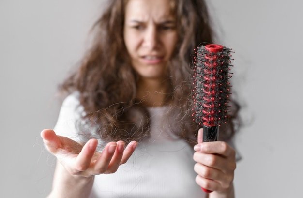Mujer usando un cepillo para desenredarse el cabello. | Foto: Freepik 