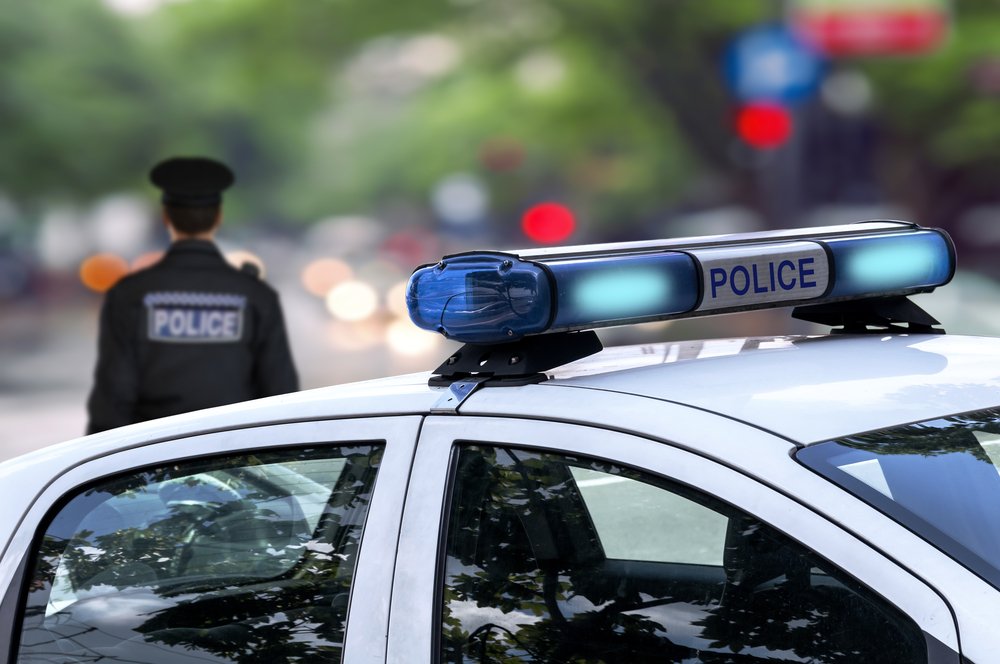 Police officer emergency service car driving street with siren light blinking | Photo: Shutterstock