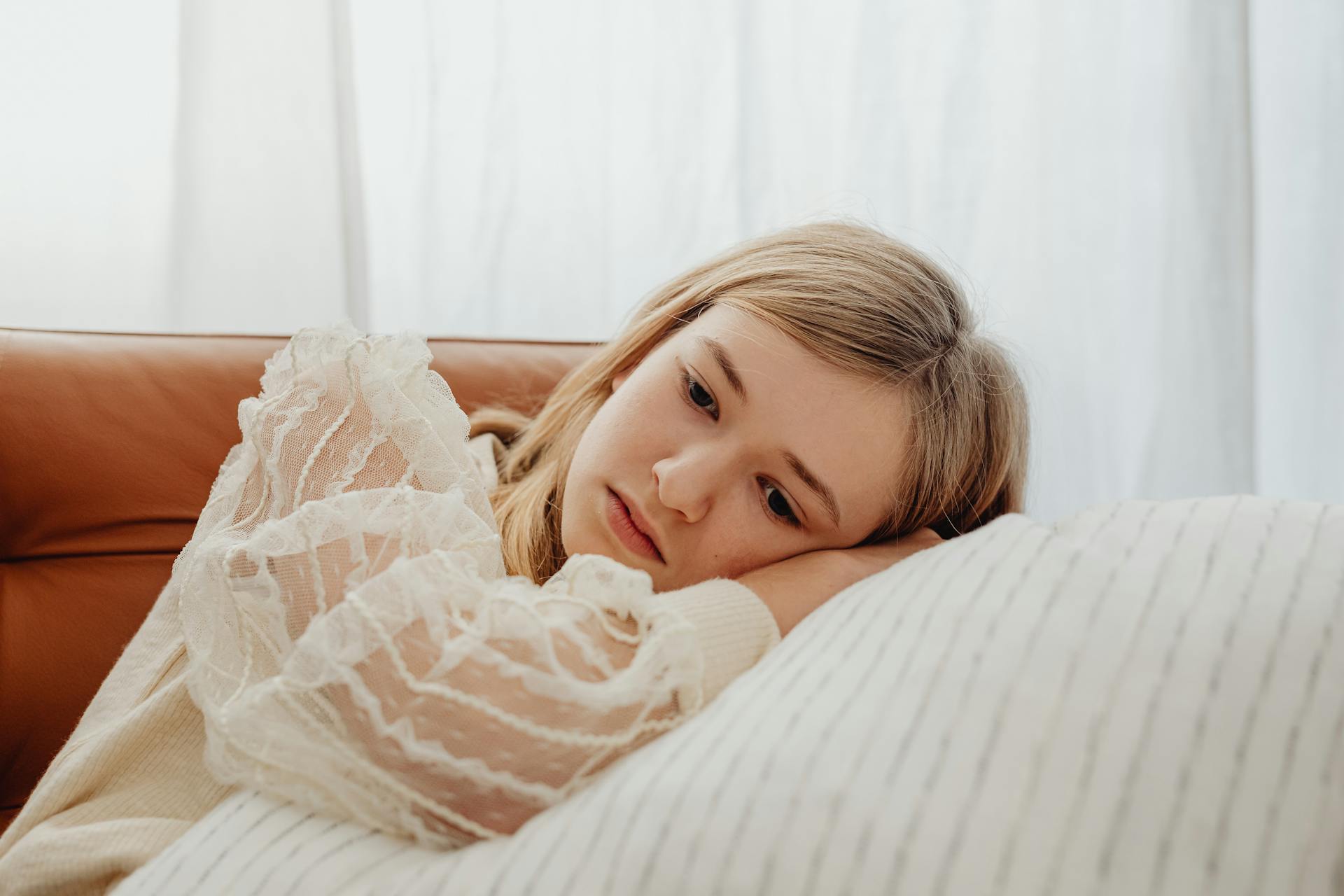 A sad teenage girl lying on a pillow | Source: Pexels