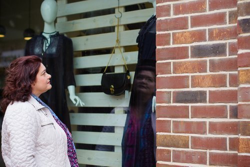 Plus sized woman looking at fashion in a store display window. | Source: Shutterstock