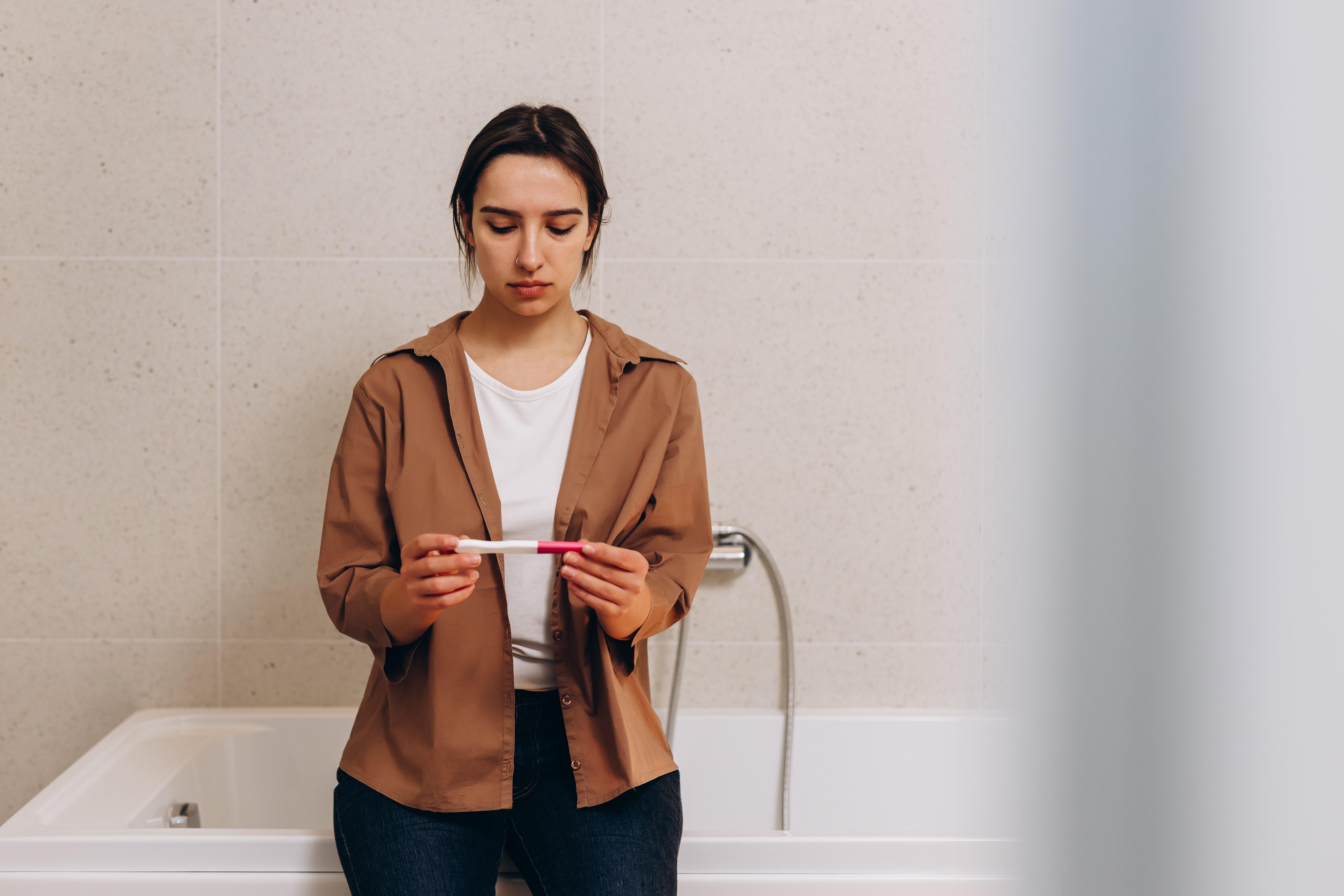 A young woman looking at a pregnancy test | Source: Shutterstock