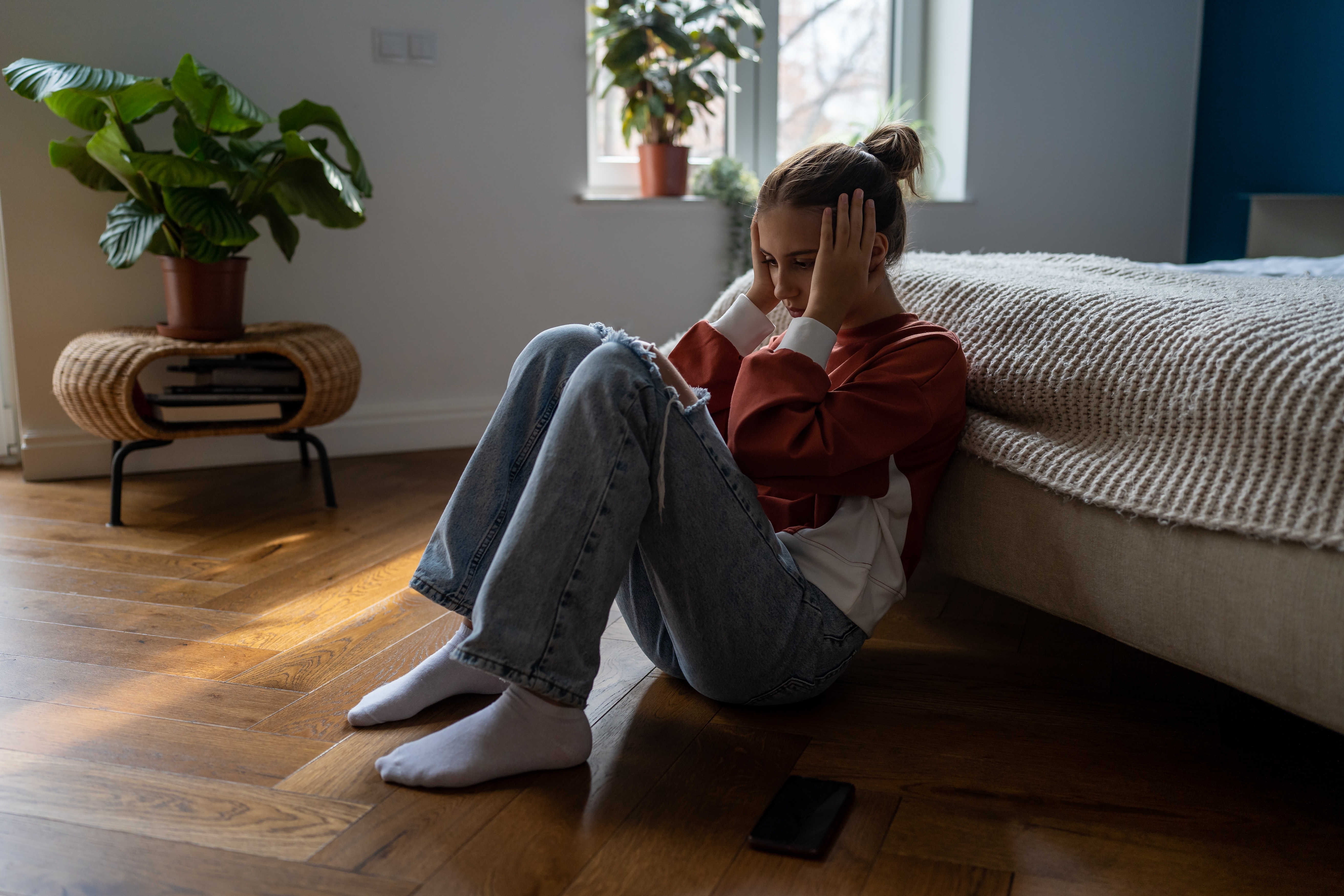 Frustrated sad teen girl child sitting alone on floor. | Source: Shutterstock