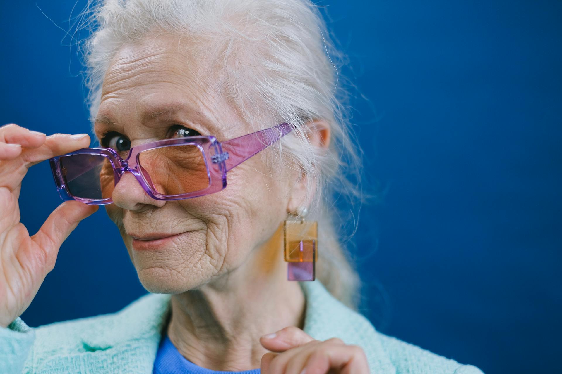 An older woman holding her eyeglasses and smiling | Source: Pexels