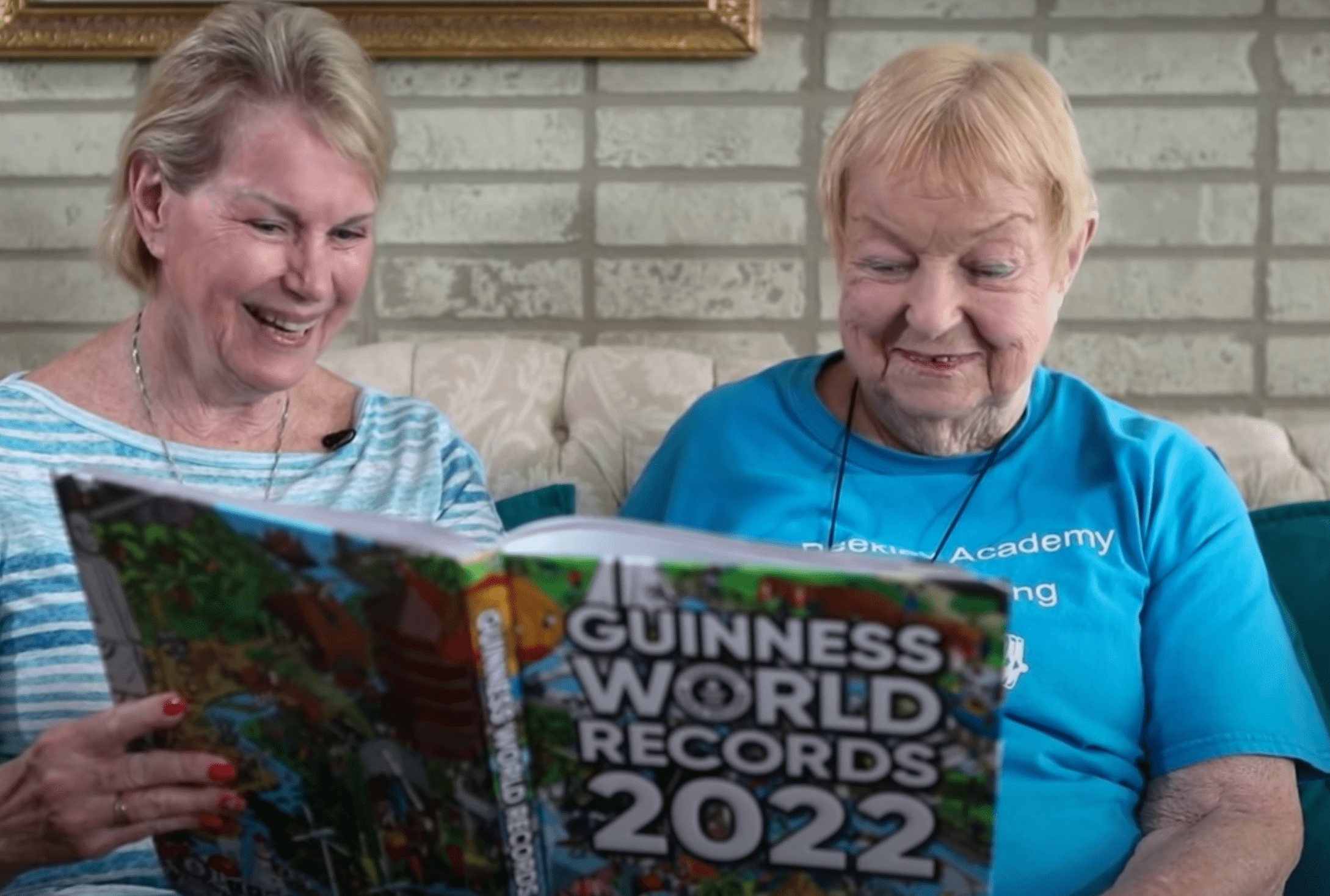 100-year-old woman and her daughter look through 2022 Guinness World Record book which honored her as a record holder for powerlifting | Photo: Youtube/Guinness World Records