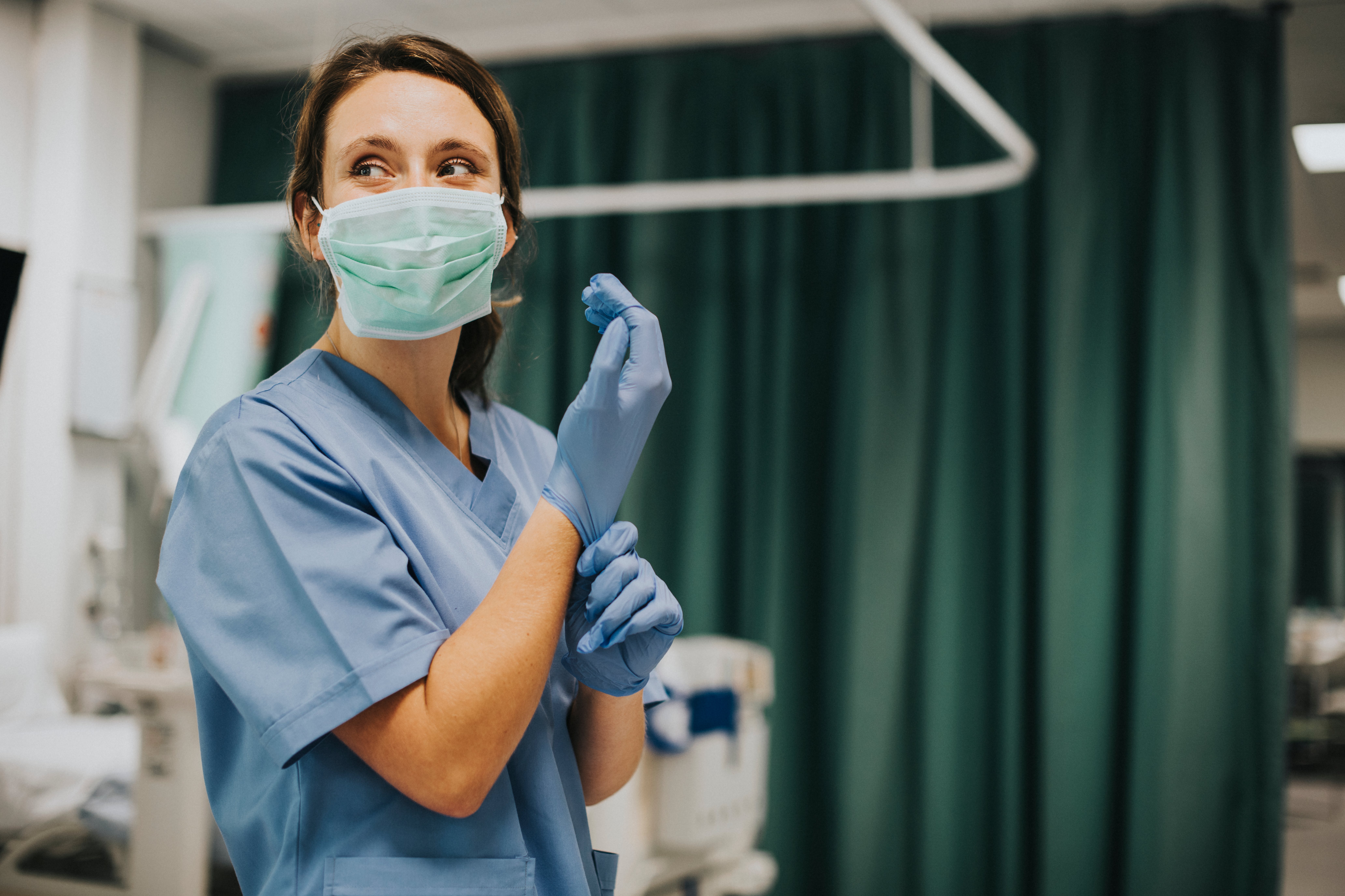 A Female nurse with a mask putting on gloves | Photo: Shutterstock