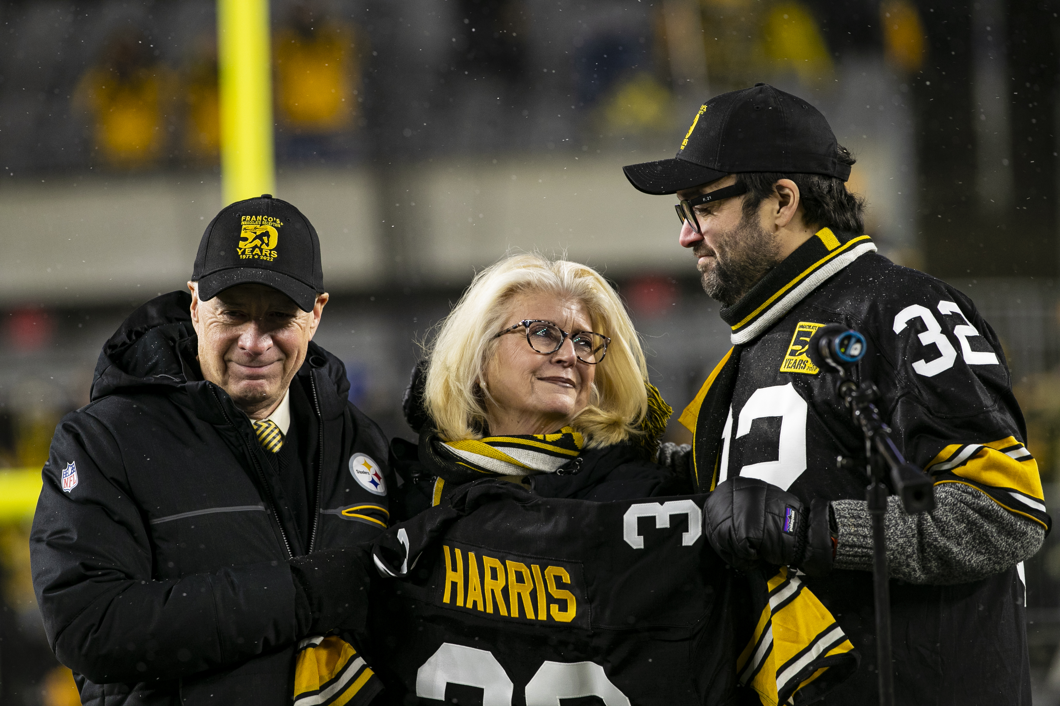 Art Rooney II presents Dana Dokmanovich and her son Franco "Dok" Dokmanovich Harris with Franco Harris's jersey during the retirement ceremony at Acrisure Stadium on December 24, 2022, in Pittsburgh, Pennsylvania. | Source: Getty Images