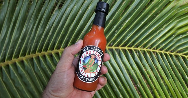 A person holds a bottle of hot sauce outdoors. | Source: Shutterstock
