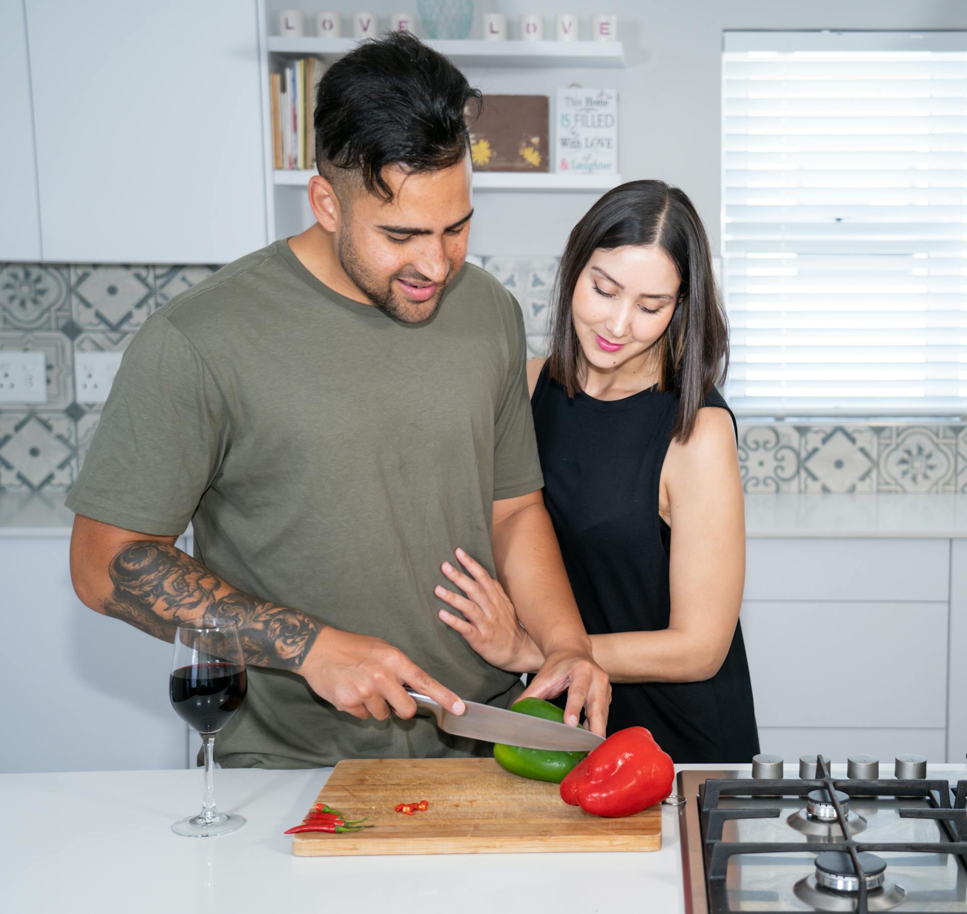 A woman watching her husband chop vegetables in the kitchen | Source: Pexels