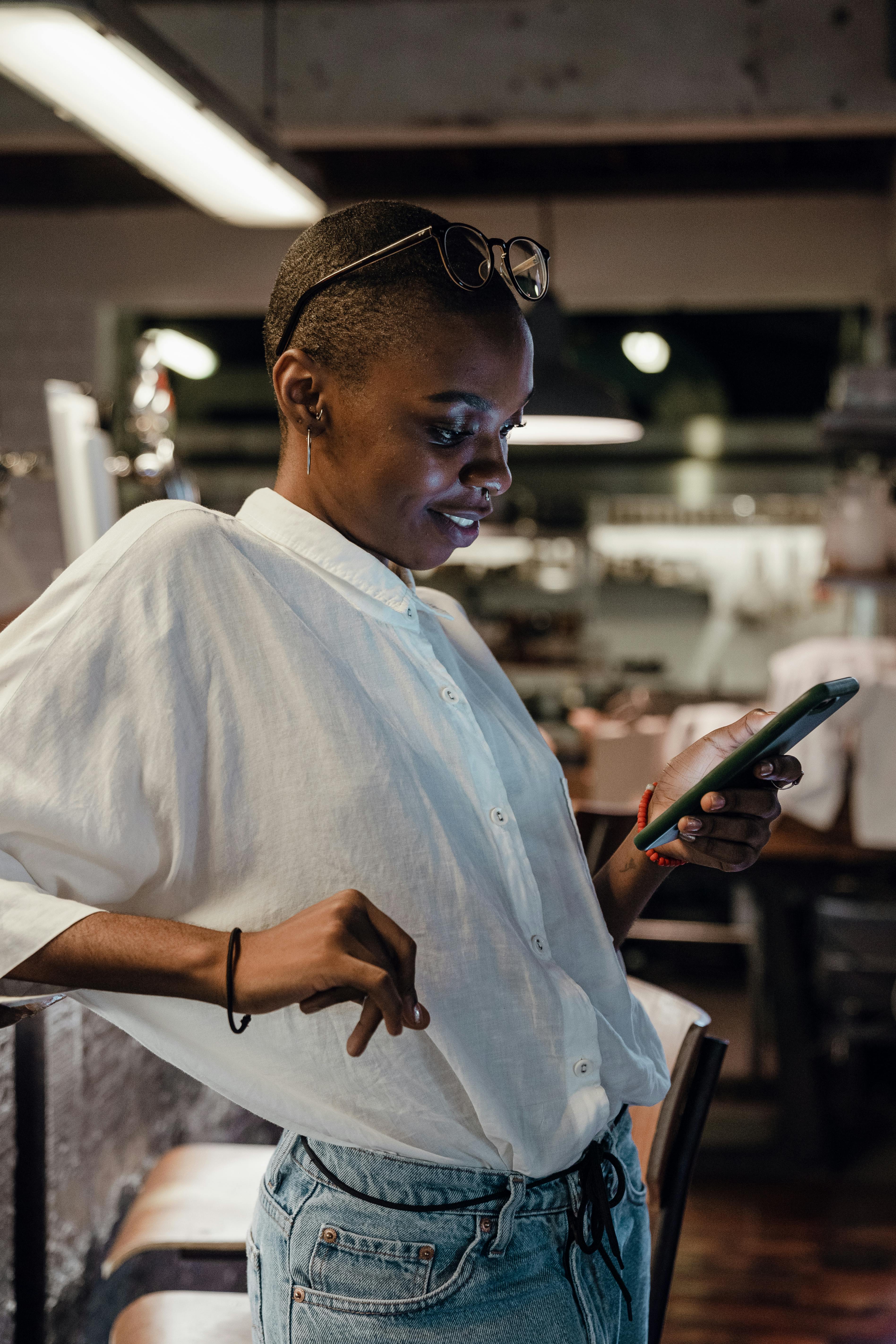 A happy woman looking at her phone at a café | Source: Pexels
