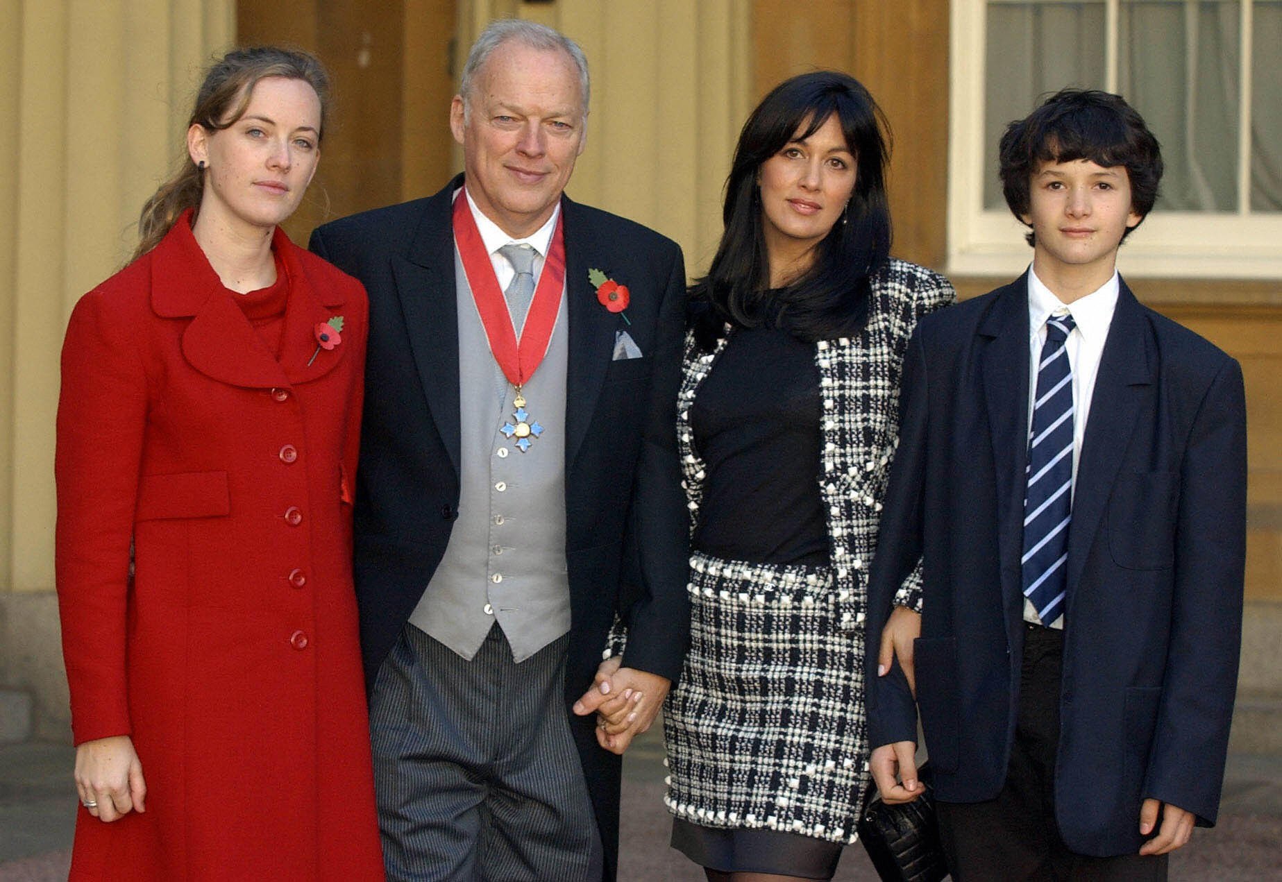 David Gilmour with Alice Gilmour (L) Polly Samson and Charlie Gilmour (R) at Buckingham Palace in London, England, on November 7, 2003. | Source: Getty Images