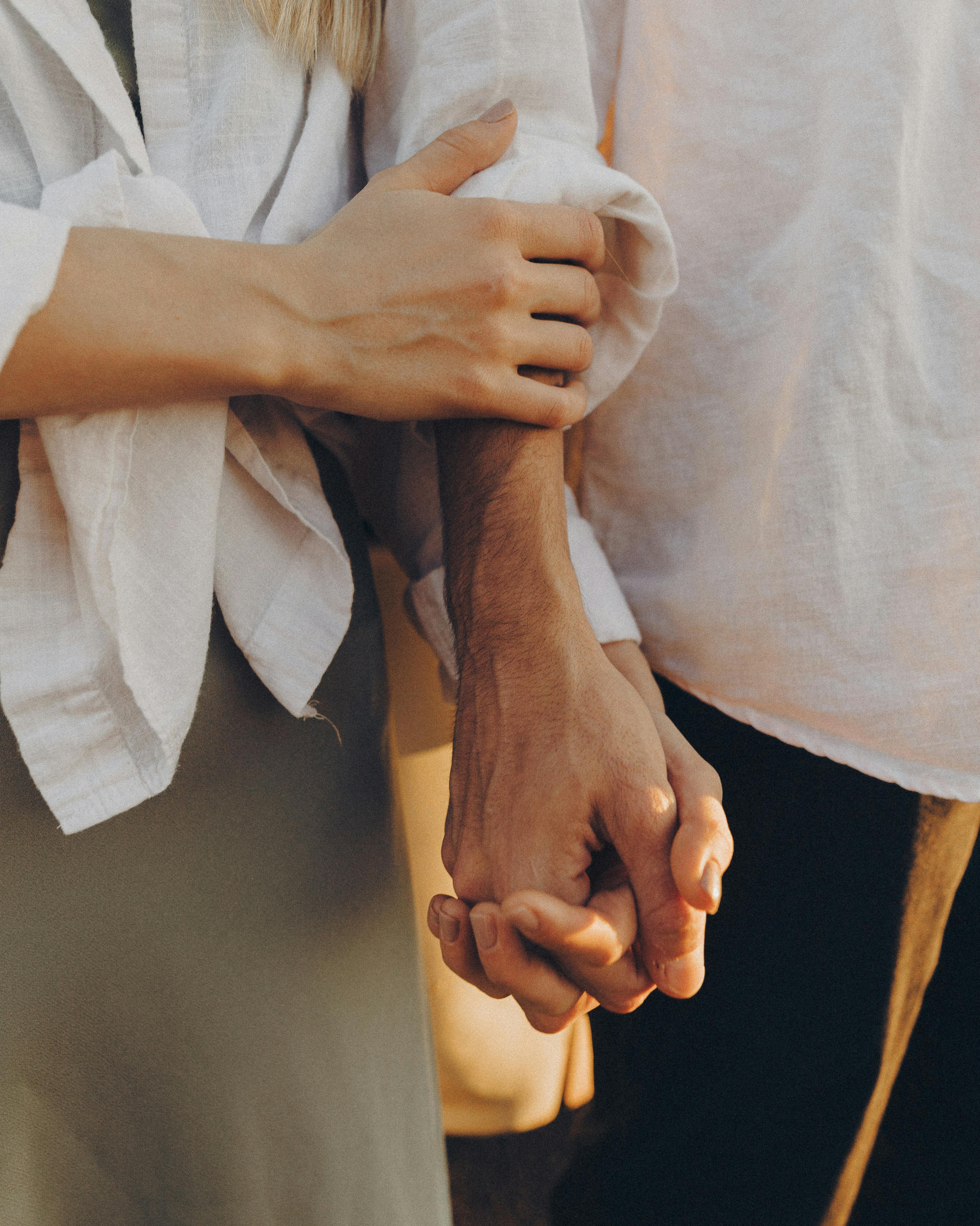 A woman caressing a man's arm while holding hands | Source: Pexels