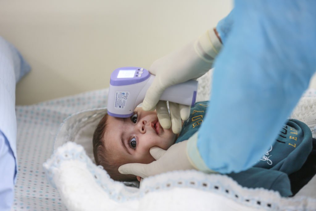 CIUDAD DE GAZA, GAZA - 18 DE MARZO: Un trabajador de la salud verifica la temperatura corporal de un bebé en una escuela que la Agencia de Obras Públicas y Socorro de las Naciones Unidas para los Refugiados de Palestina (UNRWA) convierte en una clínica para pacientes con trastornos del sistema respiratorio como medida de precaución contra El coronavirus (COVID-19) en la ciudad de Gaza, Gaza, el 18 de marzo de 2020. I Foto: Getty Images