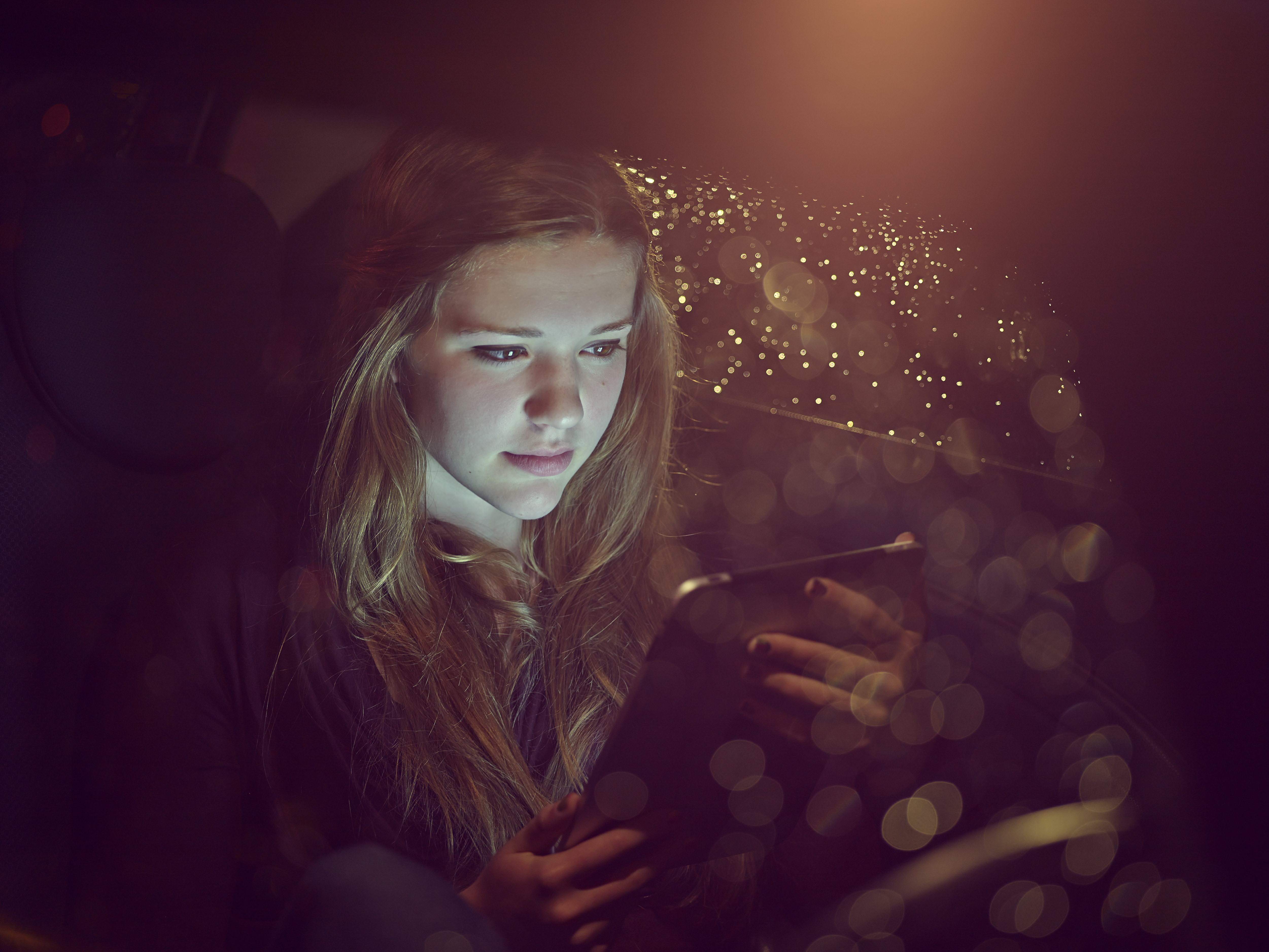 Teenage girl on an tablet computer in a car at night | Source: Getty Images