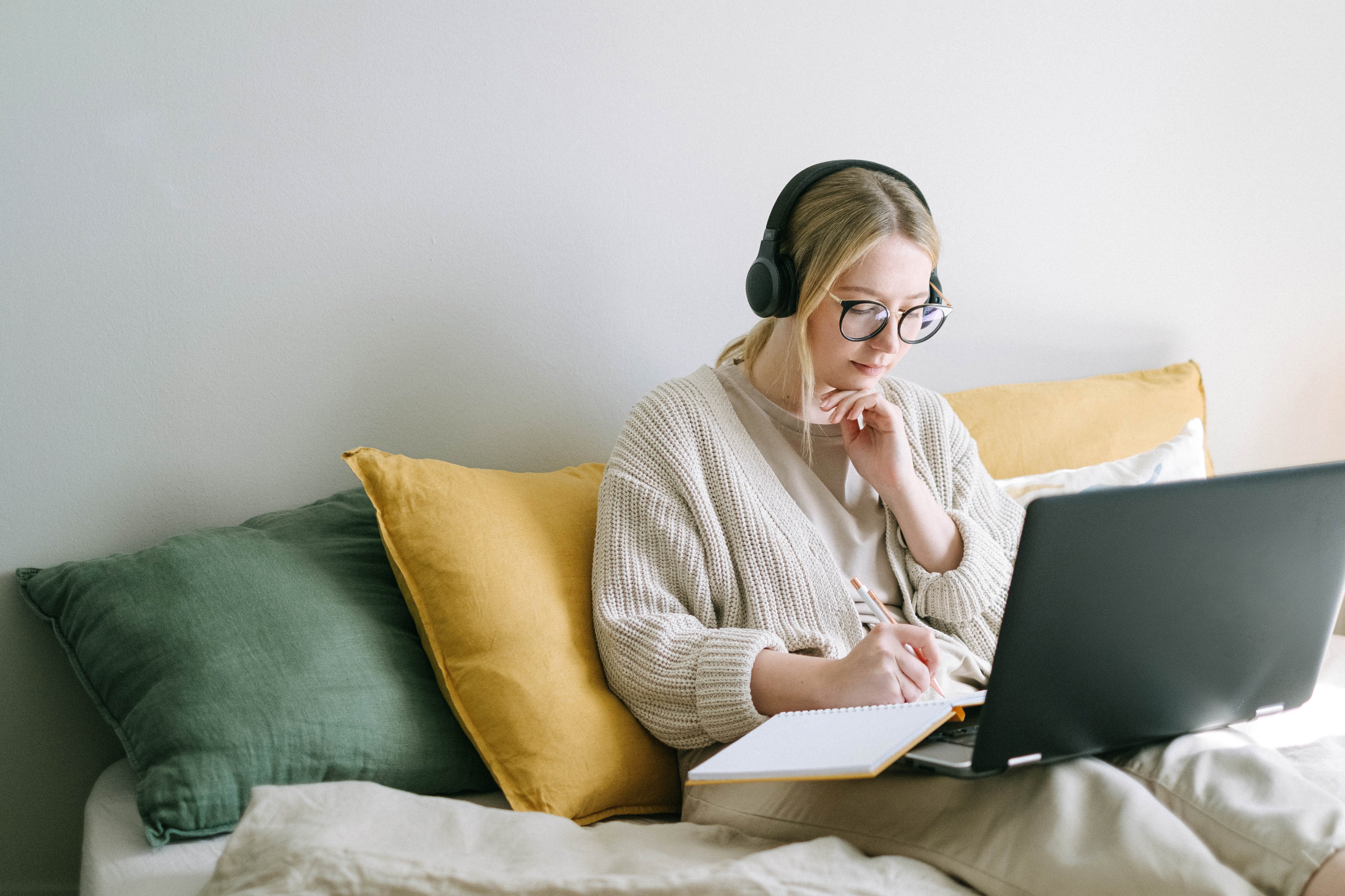 A woman with earphones working in bed | Source: Pexels