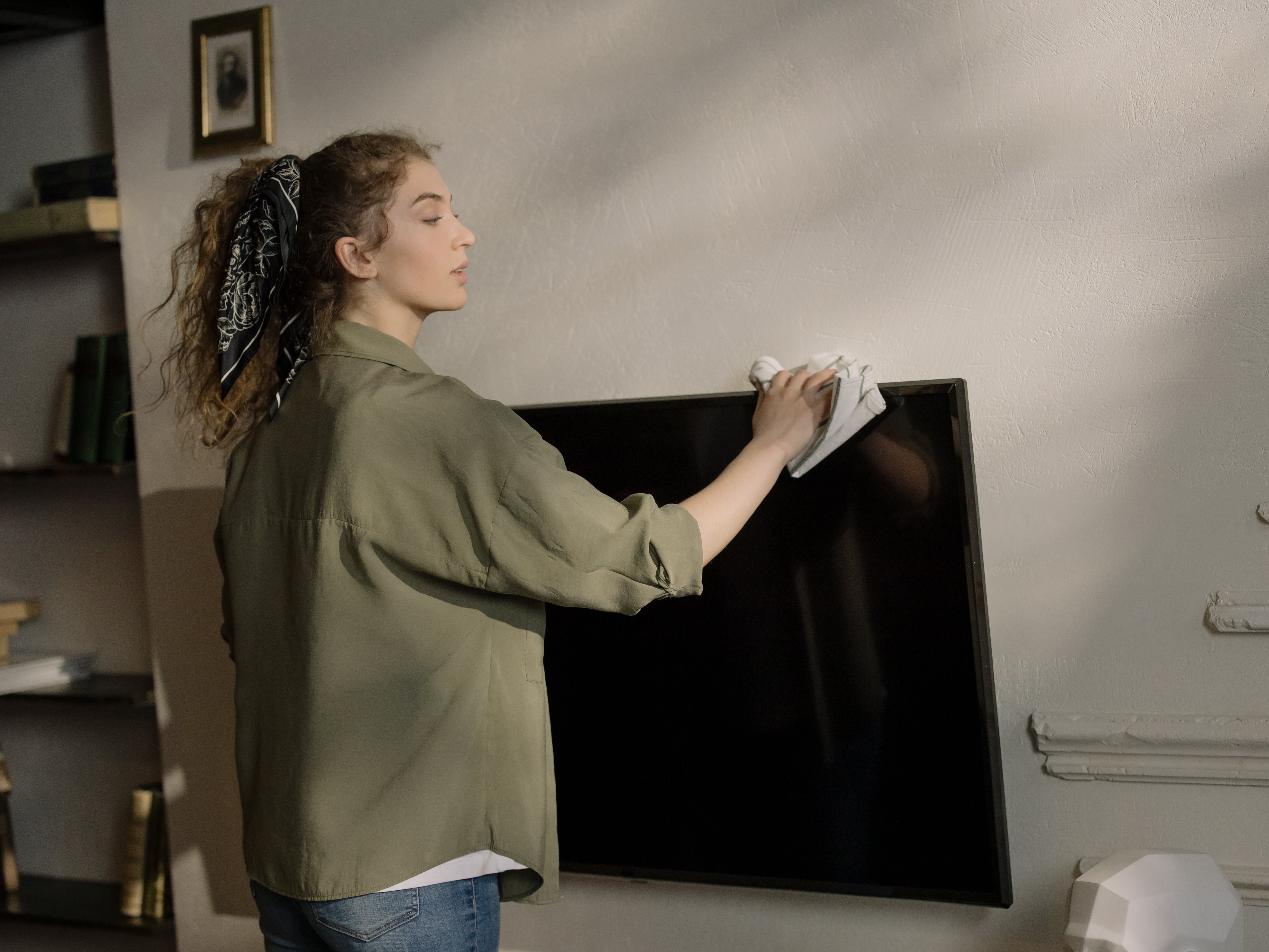 A woman standing holding a flat screen TV. | Source: Pexels