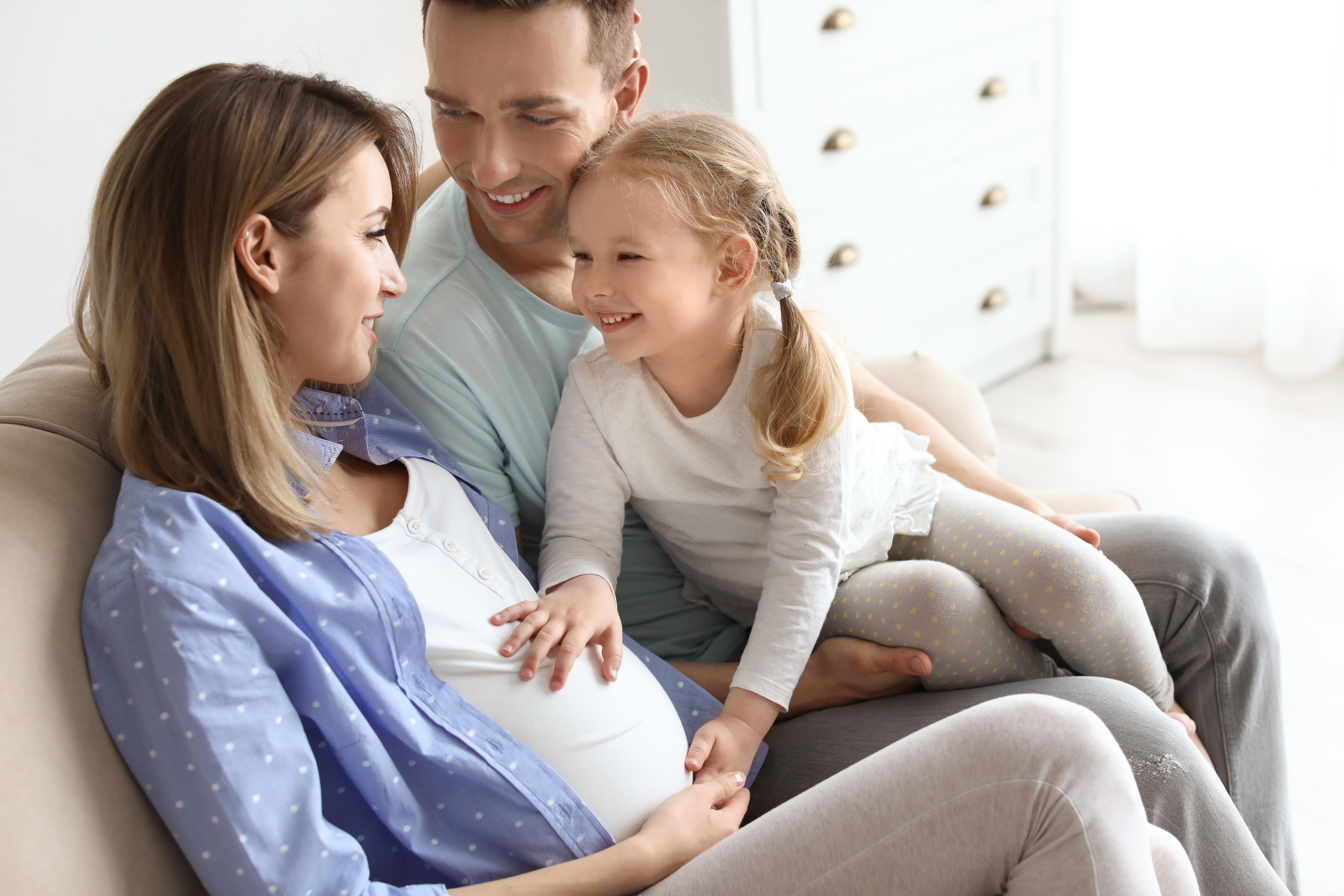 A pregnant woman with her husband and little daughter at home | Source: Shutterstock