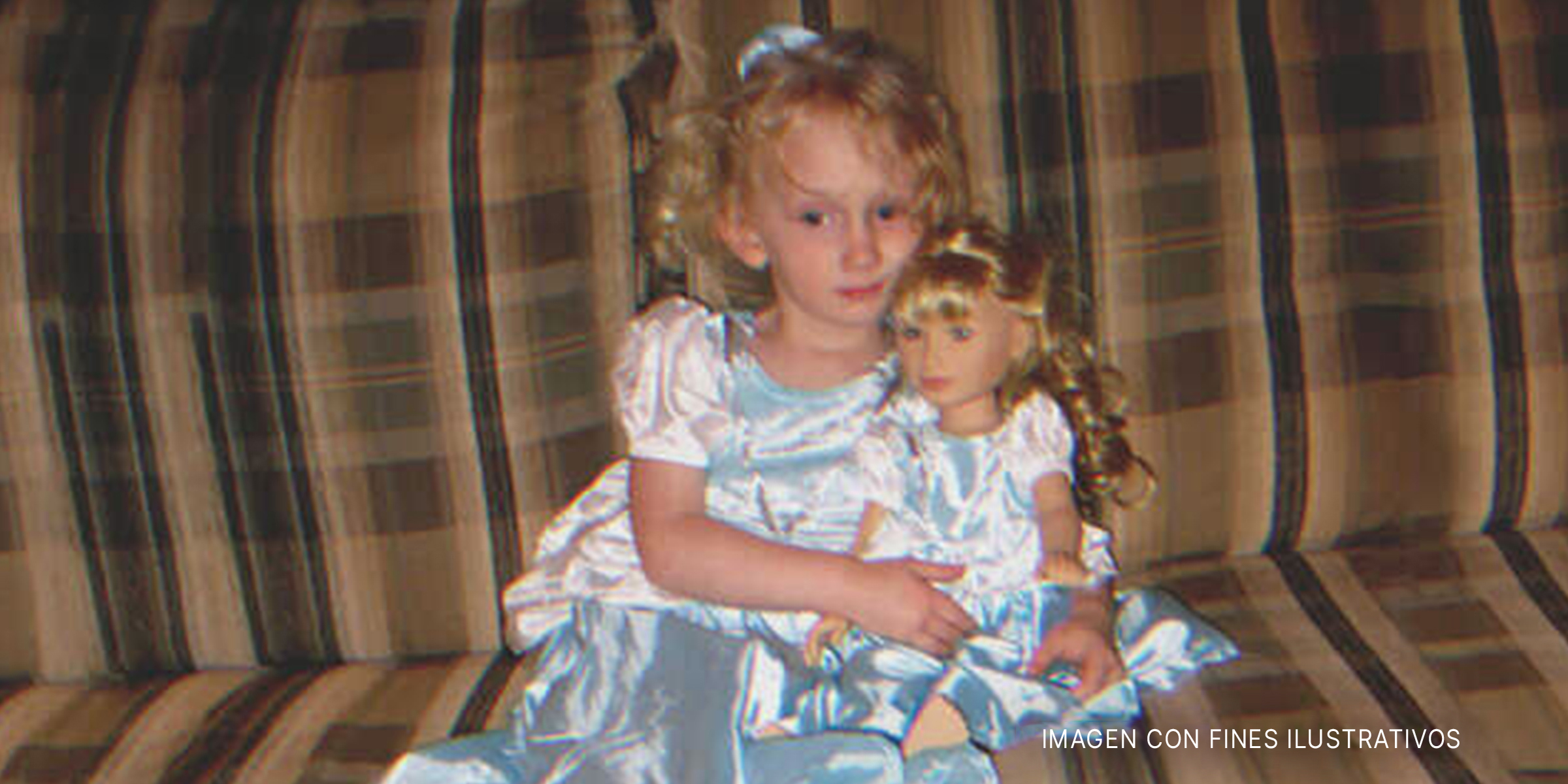 Niña en un sofá sosteniendo una muñeca. | Foto: flickr.com/Elizabeth/Table4Five (CC BY 2.0)