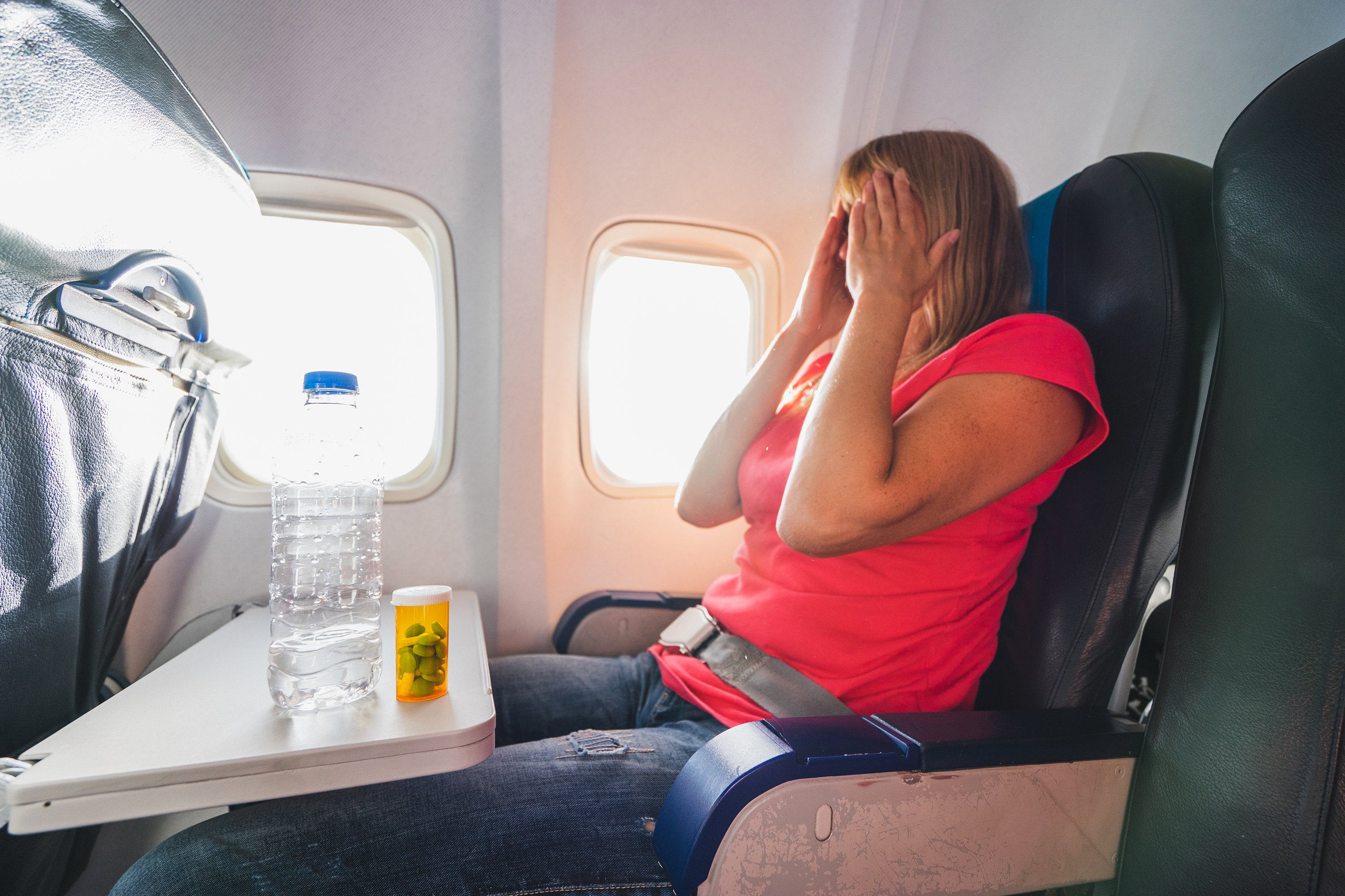 Mujer frustrada en avión con sedantes y agua. | Foto: Getty Images