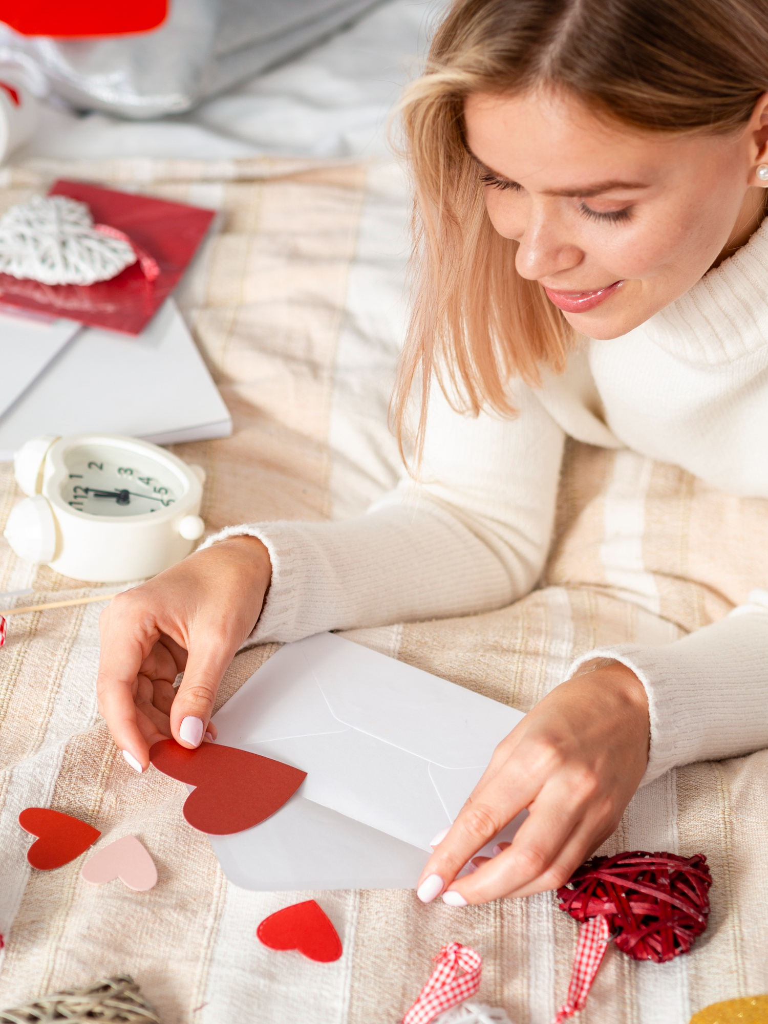 A woman placing a heart shaped piece of paper inside an envelope | Source: Freepik