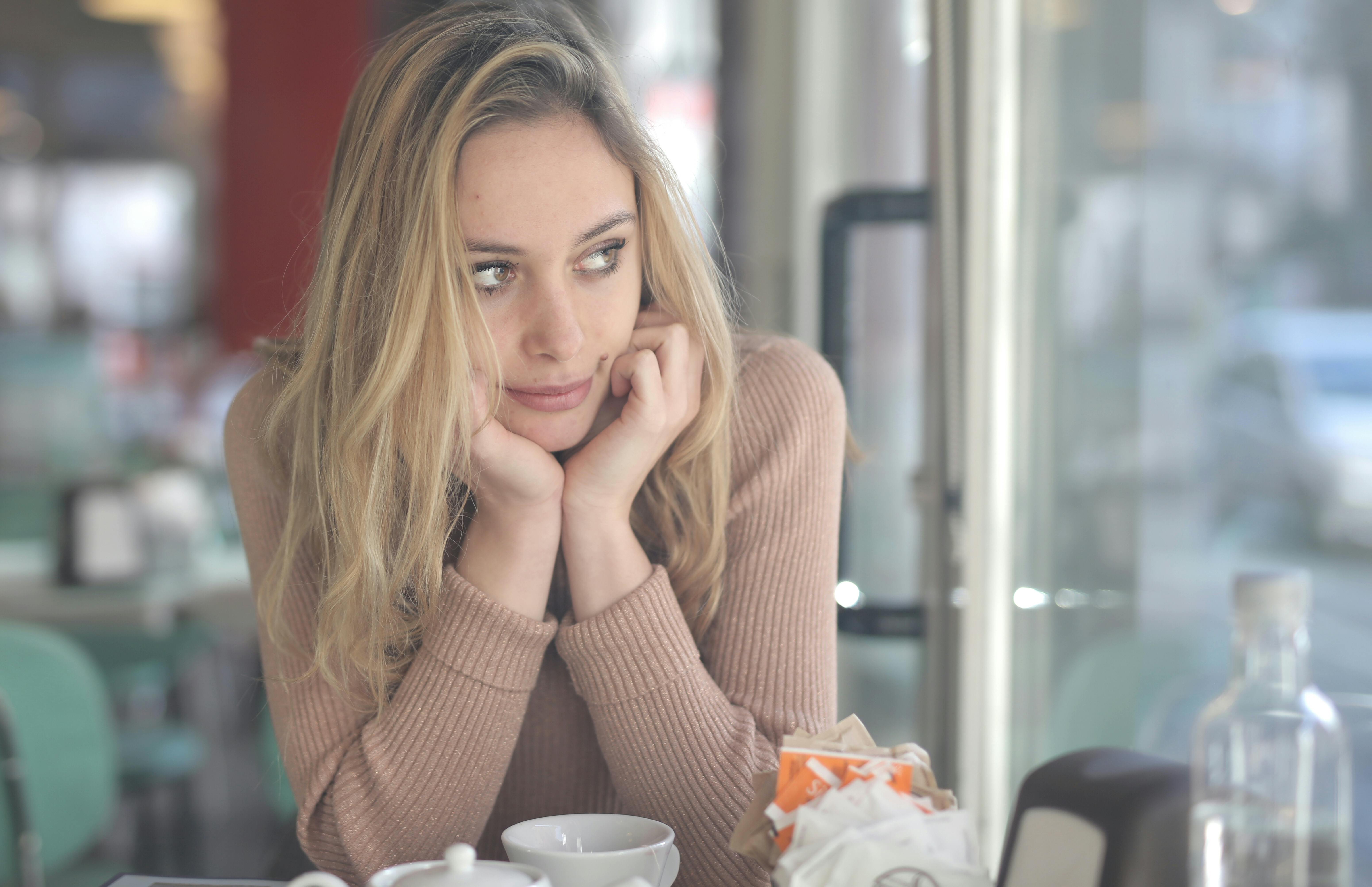 Woman in Brown Sweater Sitting by the Table | Source: Pexels