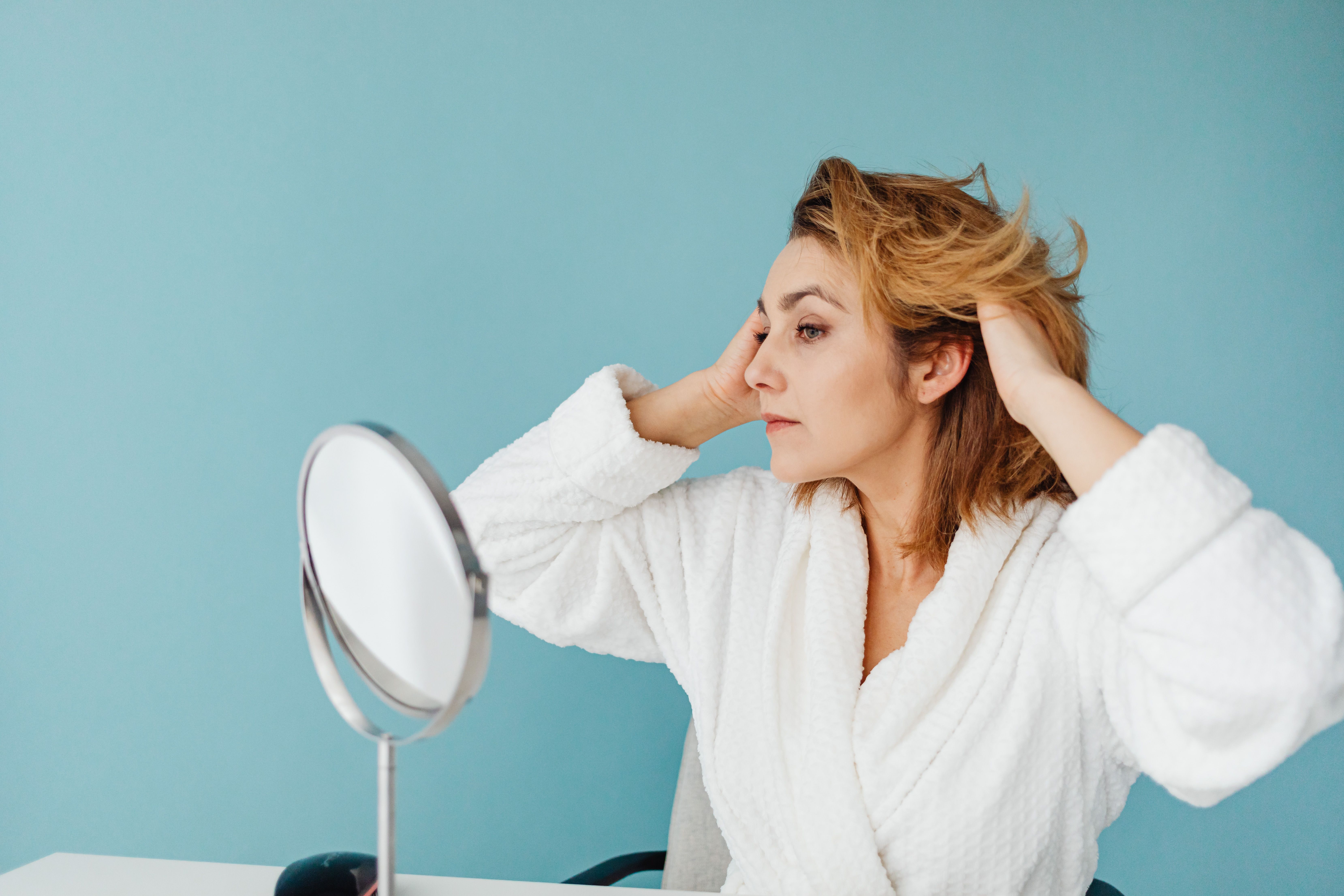 A woman admiring her hair in the mirror | Source: Pexels