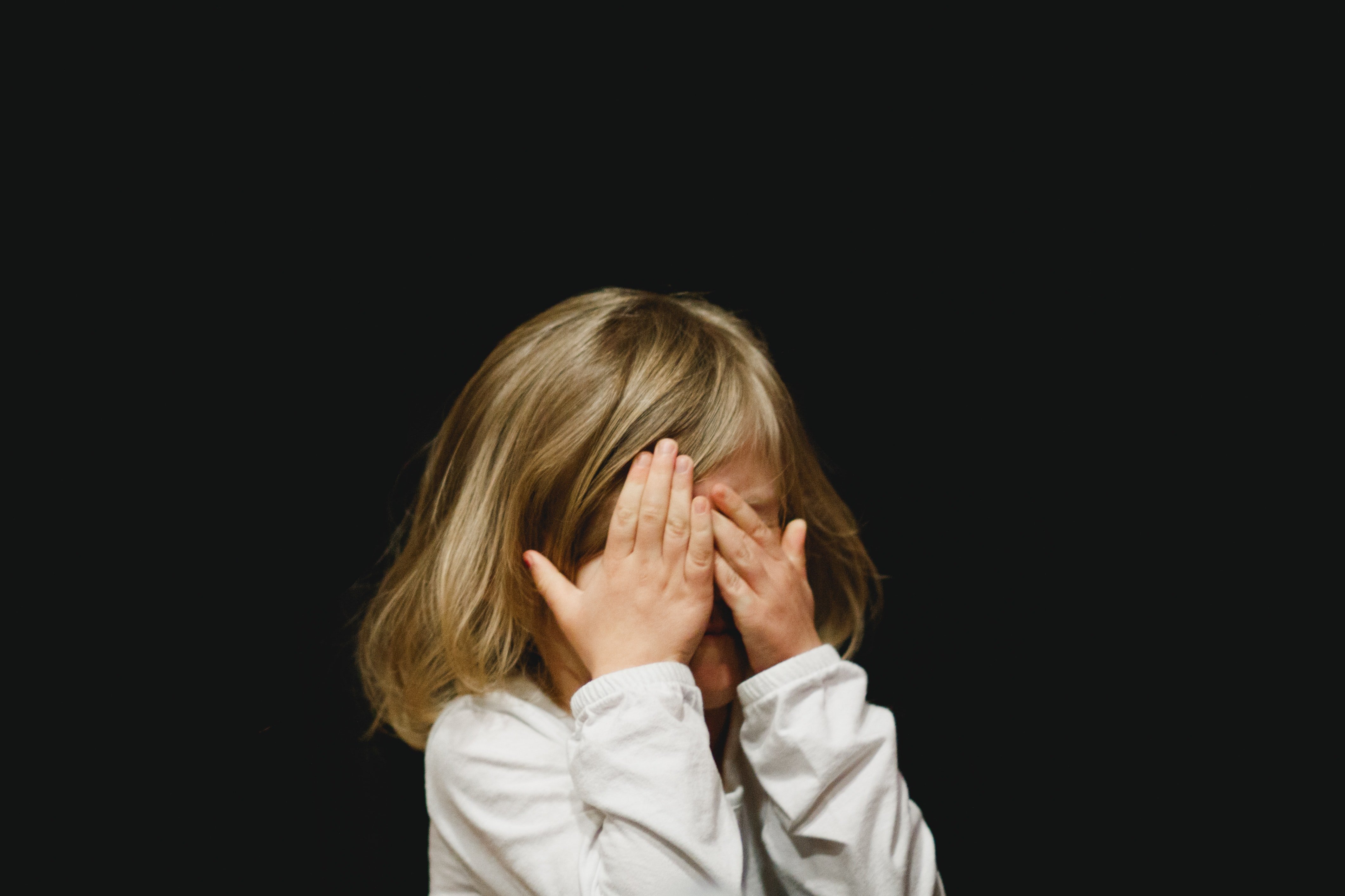 Una niña afligida llorando con sus manos sobre sus ojos. | Foto: Unsplash