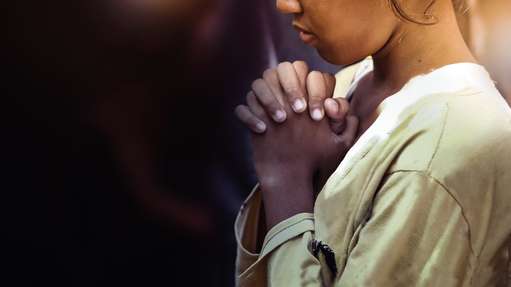 Woman with hands clasped in prayer | Photo: Shutterstock