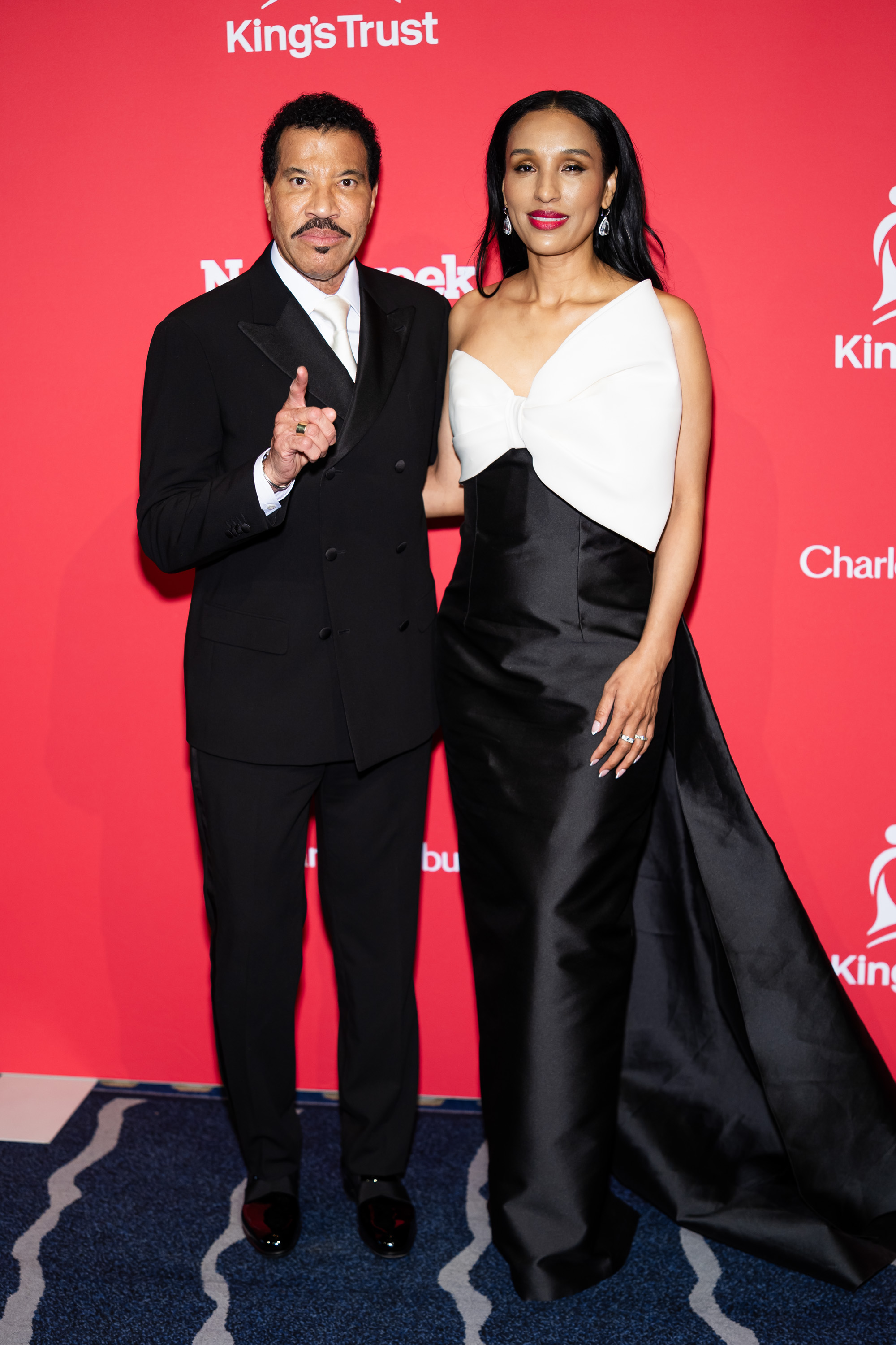Another full shot shows Richie pointing at something off-camera, yet his hand remains gently on Parigi’s waist, a quiet gesture that shows he’s still attuned to her presence.