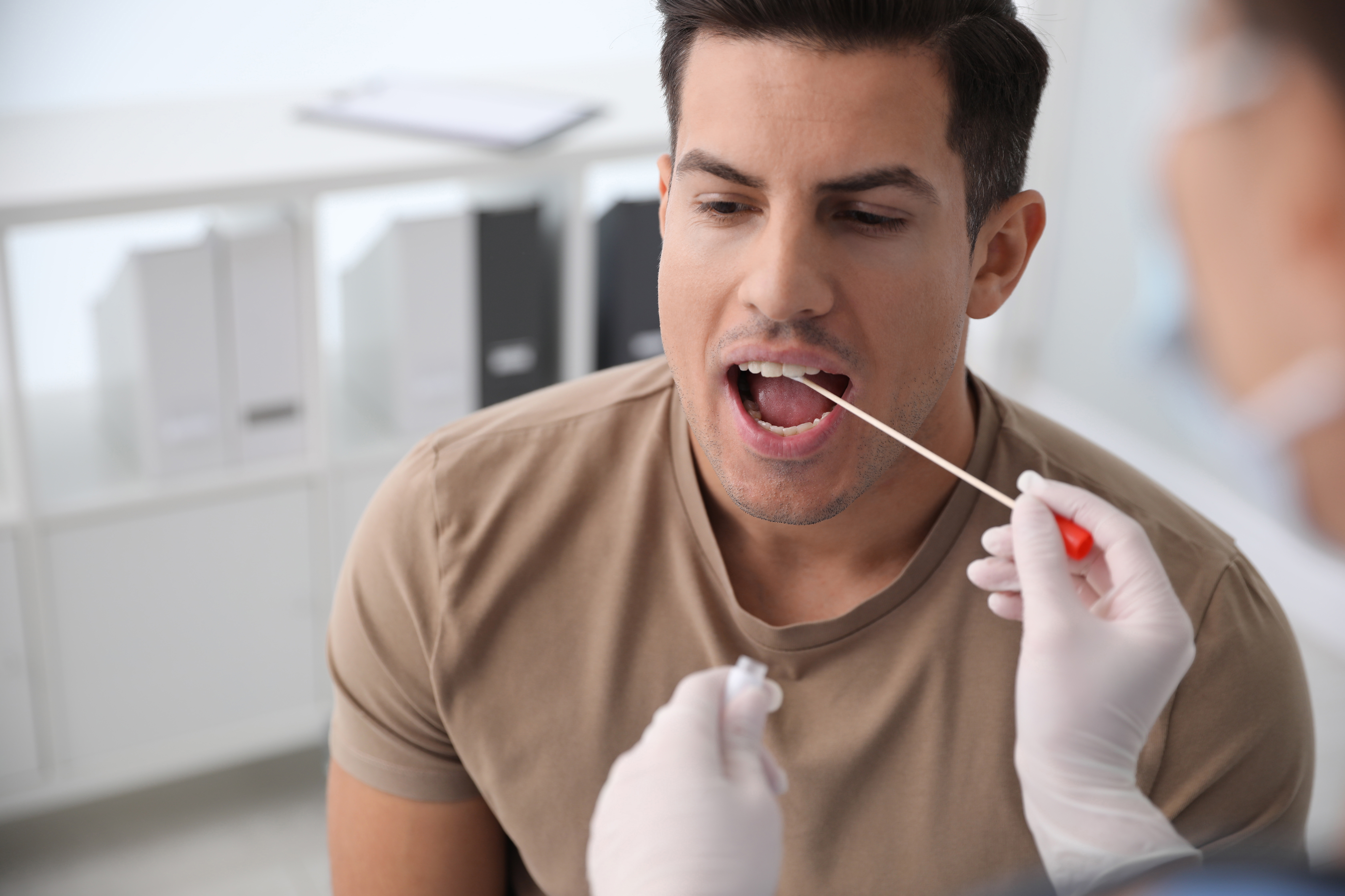 Doctor taking sample for DNA test from a man in clinic | Source: Shutterstock