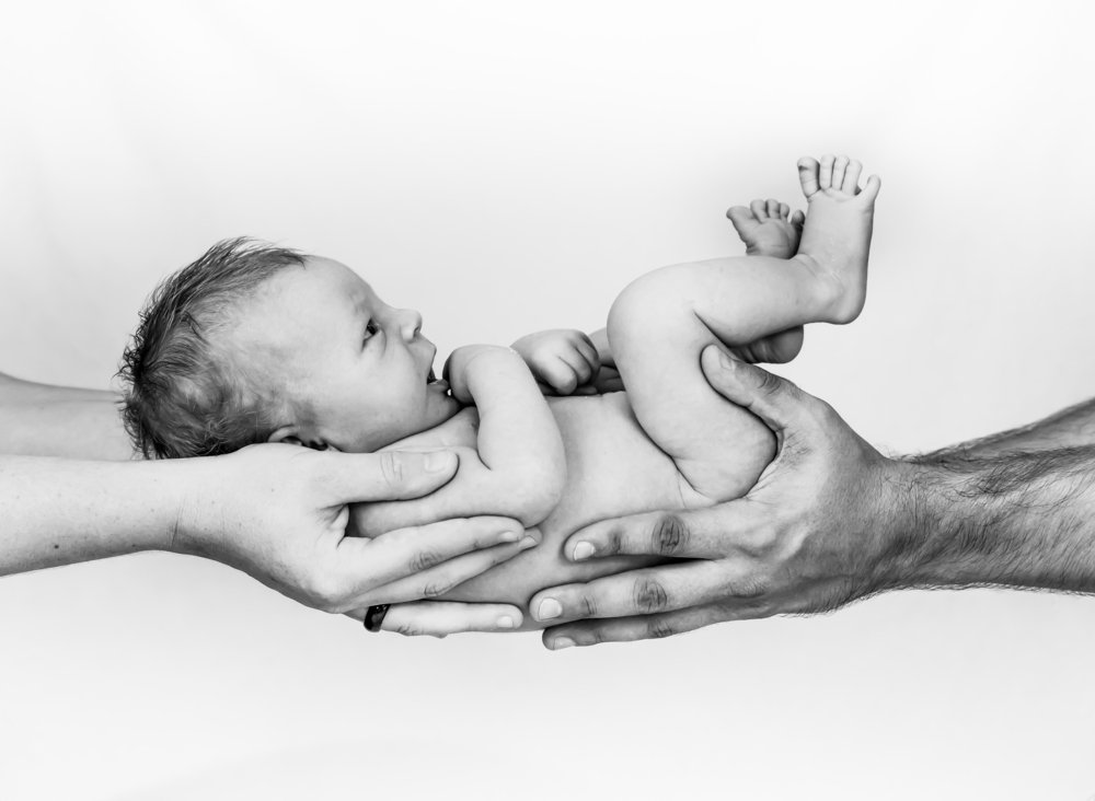 A mother and father's hands holding a newborn baby | Photo: Shutterstock/Simon Dannhauer