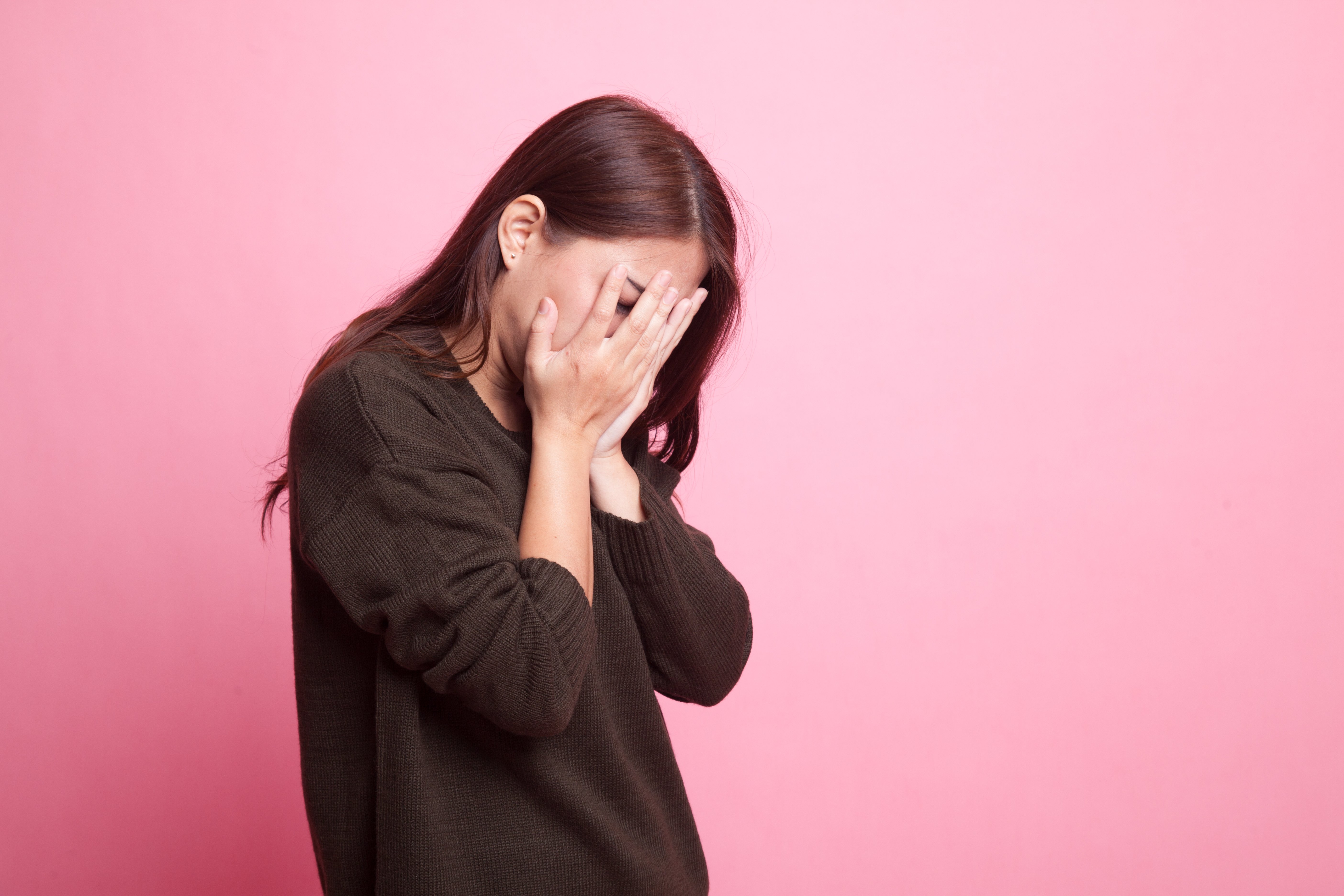 Traurige junge Frau, die mit der Handfläche zum Gesicht weint | Quelle: Shutterstock