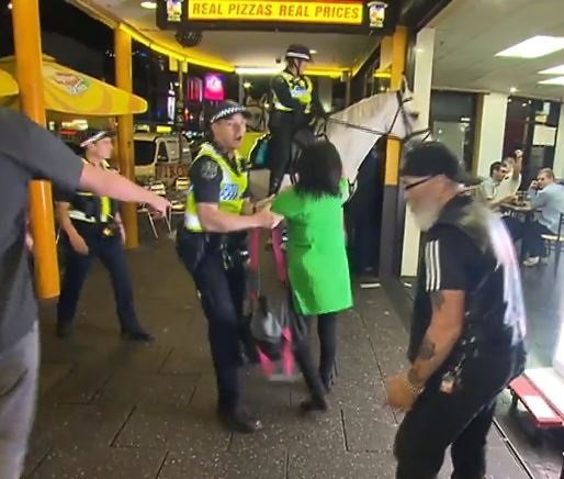 Los oficiales sacan a la mujer detenida del restaurante. Fuente: YouTube / World Today