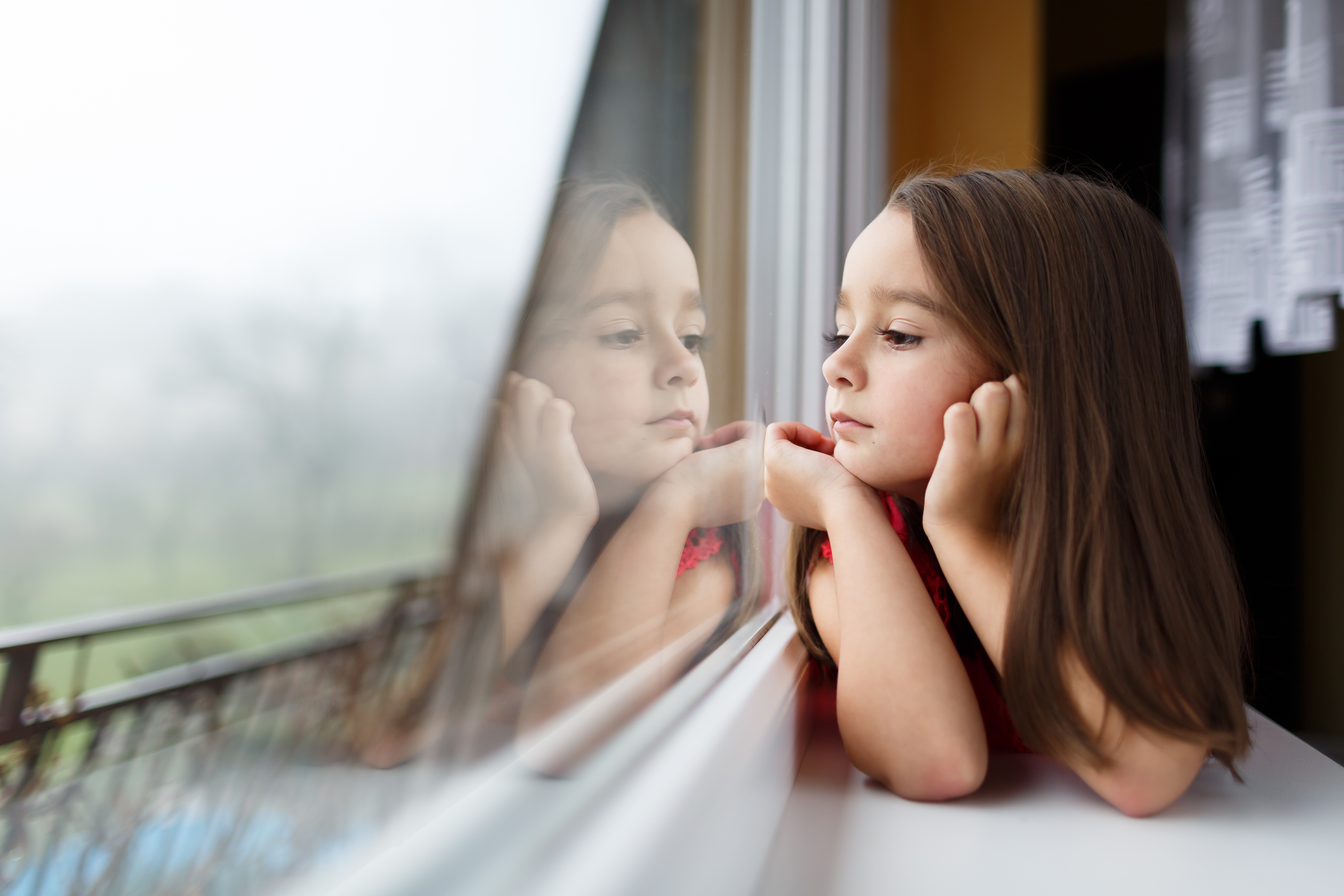 Little girl looking out the window | Source: Shutterstock