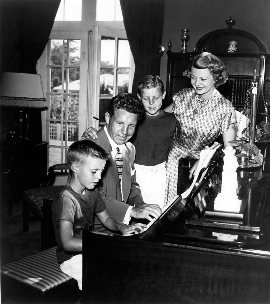 Ricky Nelson, Ozzie Nelson, David Nelson and Harriet Nelson gather round the piano as Ricky plays in circa 1946 in Los Angeles, California | Photo: Getty Images