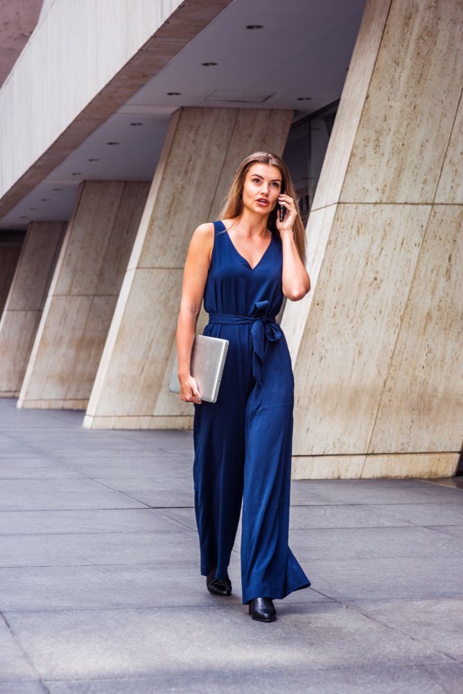 Mujer hablando por teléfono mientras camina, usando un jumper de color azul. | Foto: Shutterstock