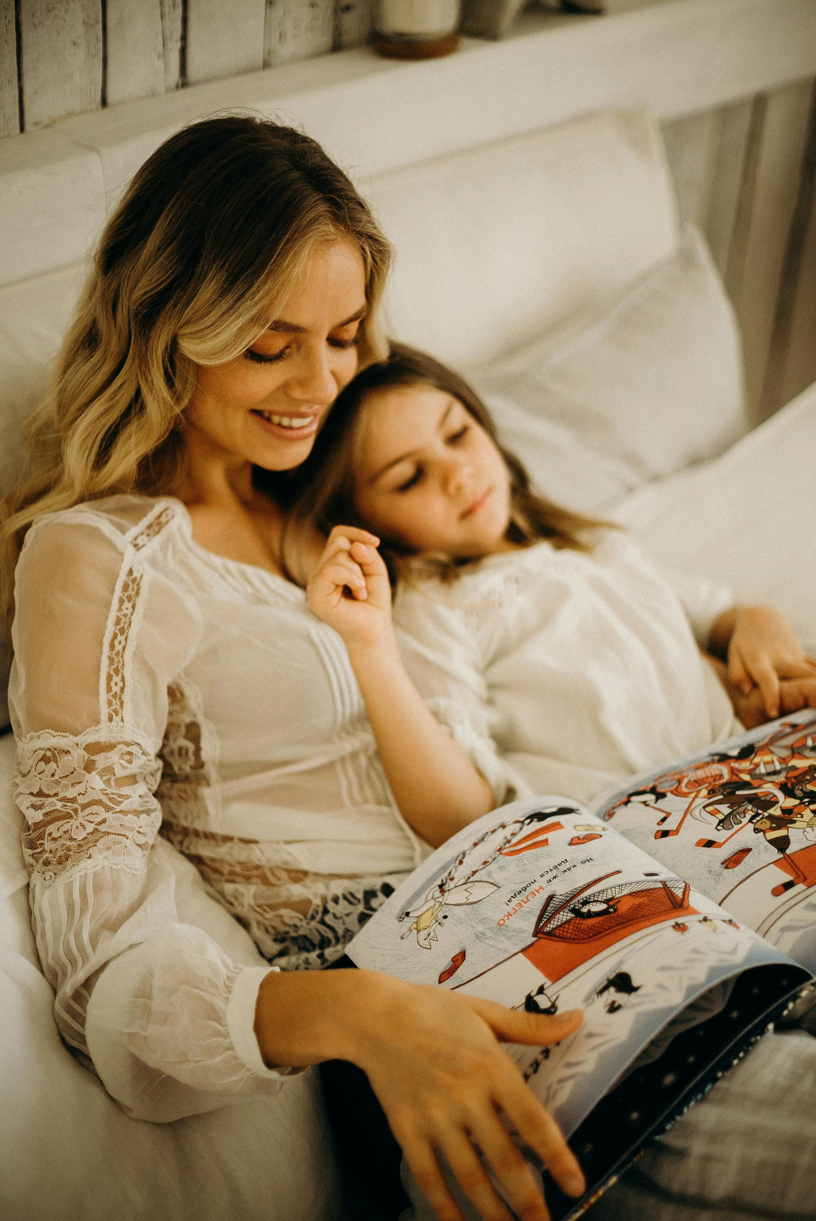 A woman tucking a little girl into bed | Source: Pexels