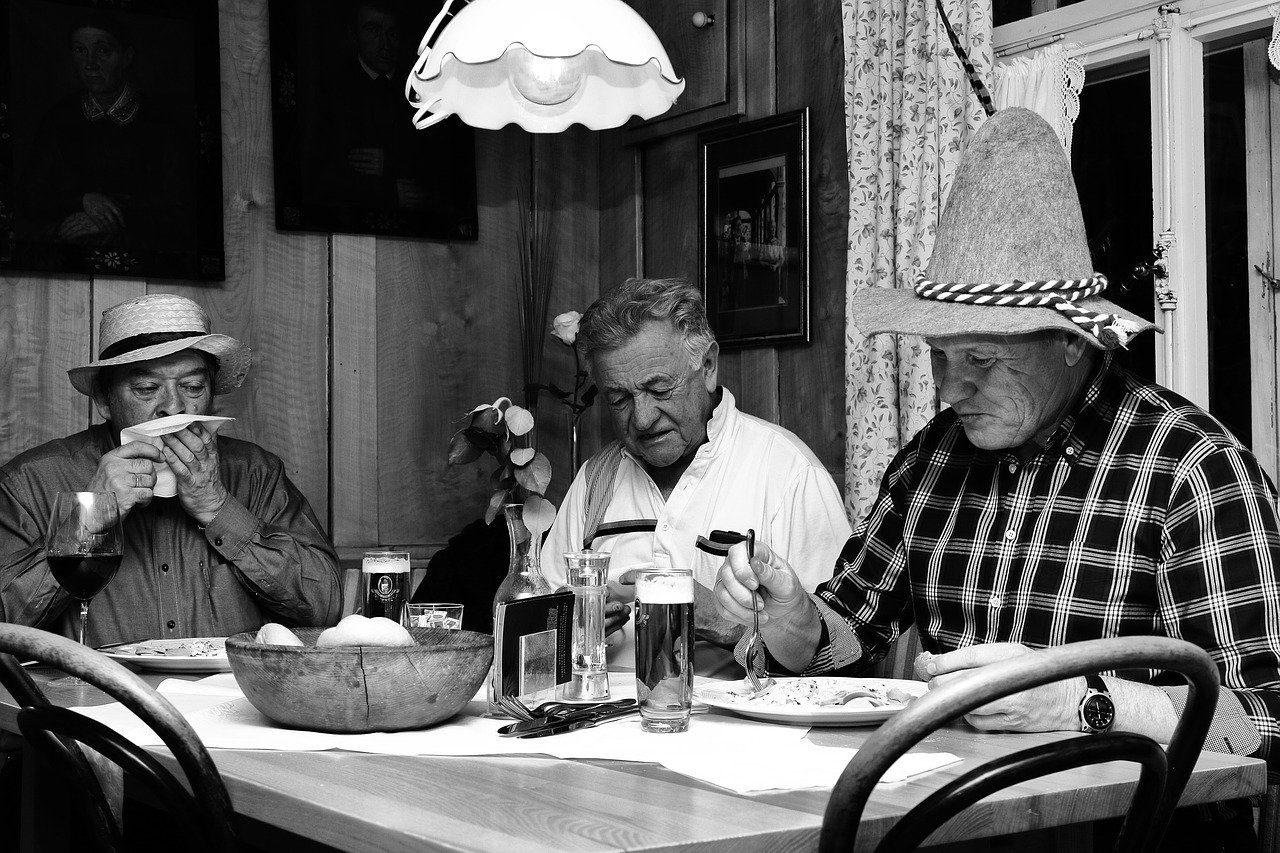 Three men having a hearty meal together in a black-and-white image | Photo: Pixabay/Kelly van de Ven