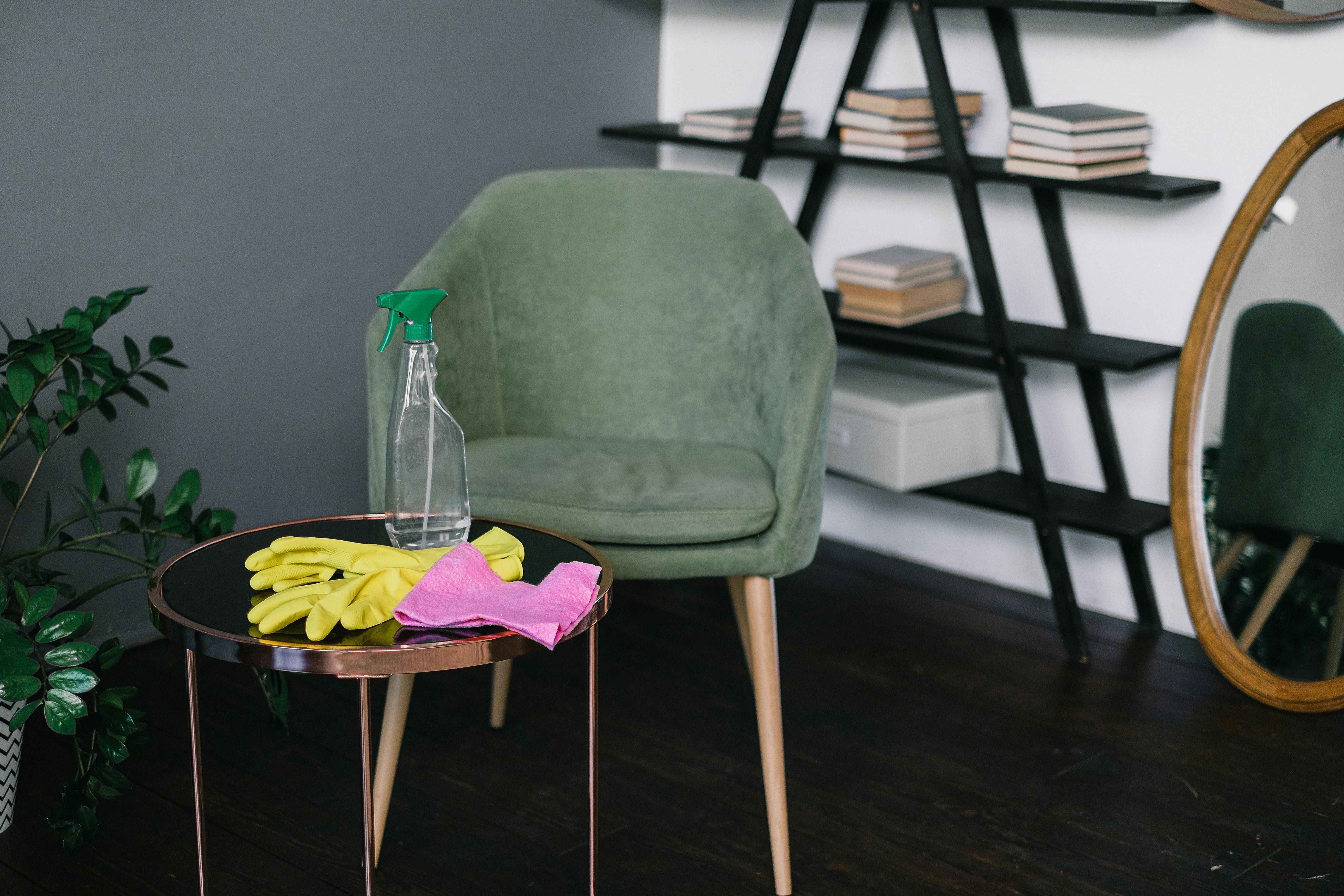 A chair with a spray, a cloth, and gloves close by | Source: Pexels