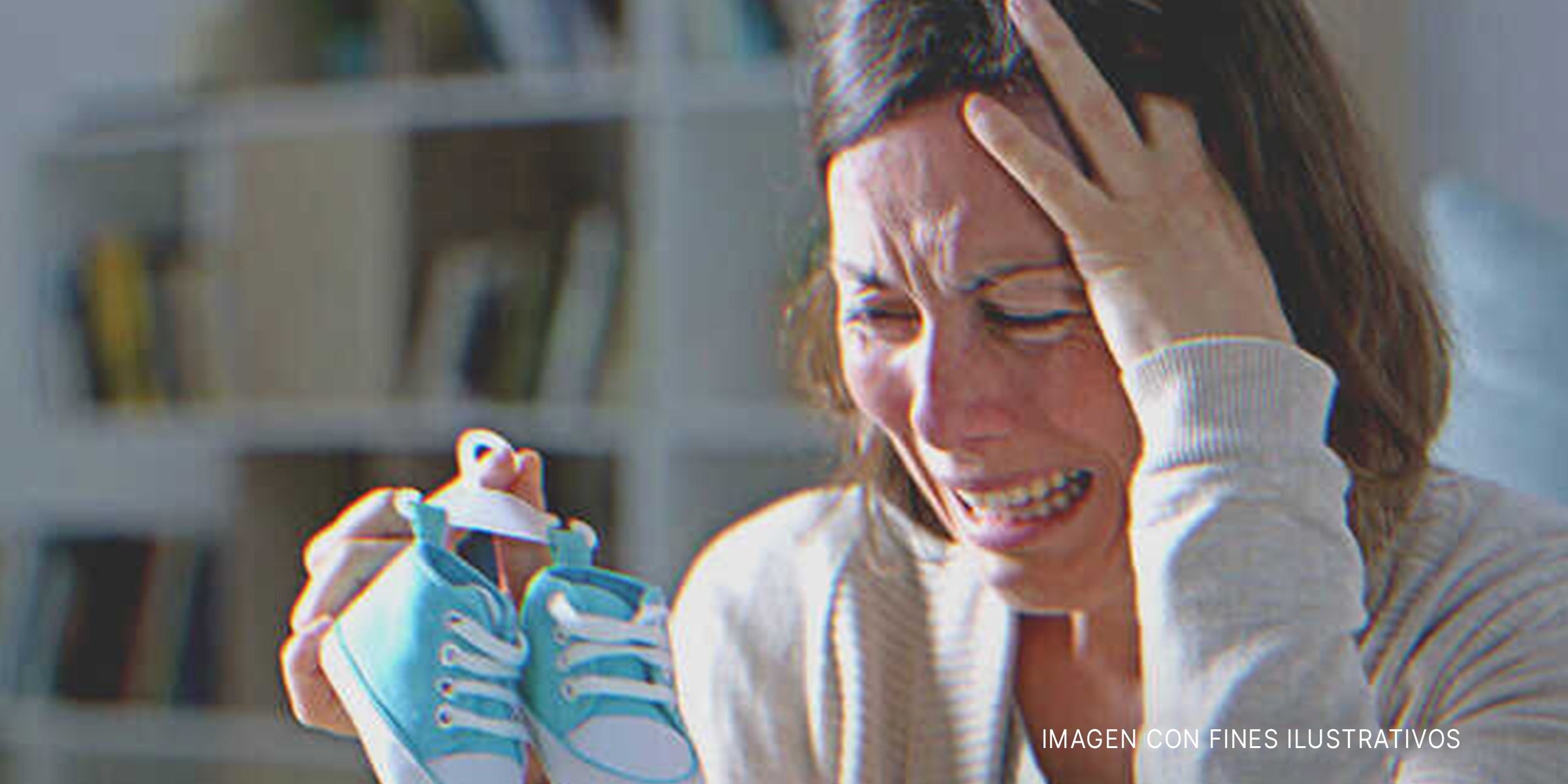 Una madre afligida sosteniendo un par de zapatos de niño. | Foto: Shutterstock
