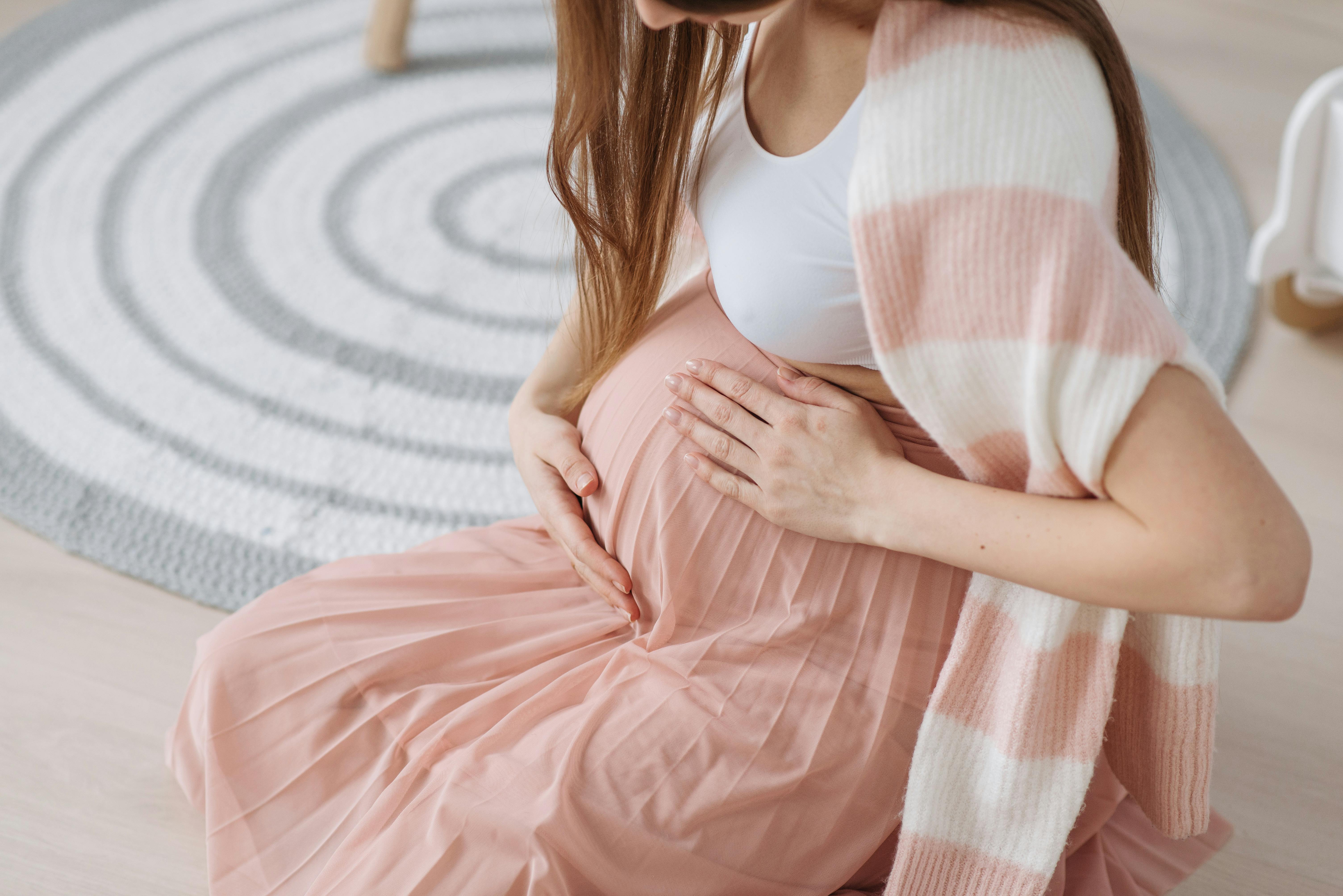 A pregnant woman holding her belly while seated | Source: Pexels