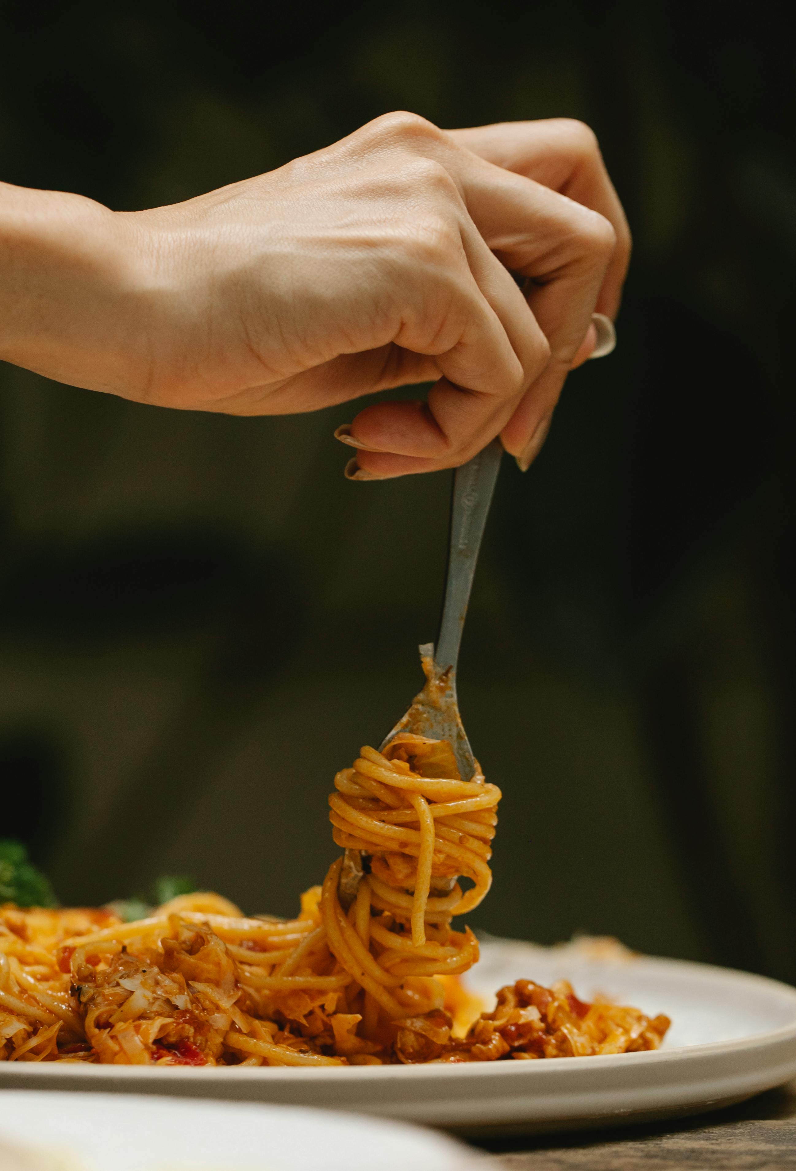 Woman rolling spaghetti on fork | Source: Pexels