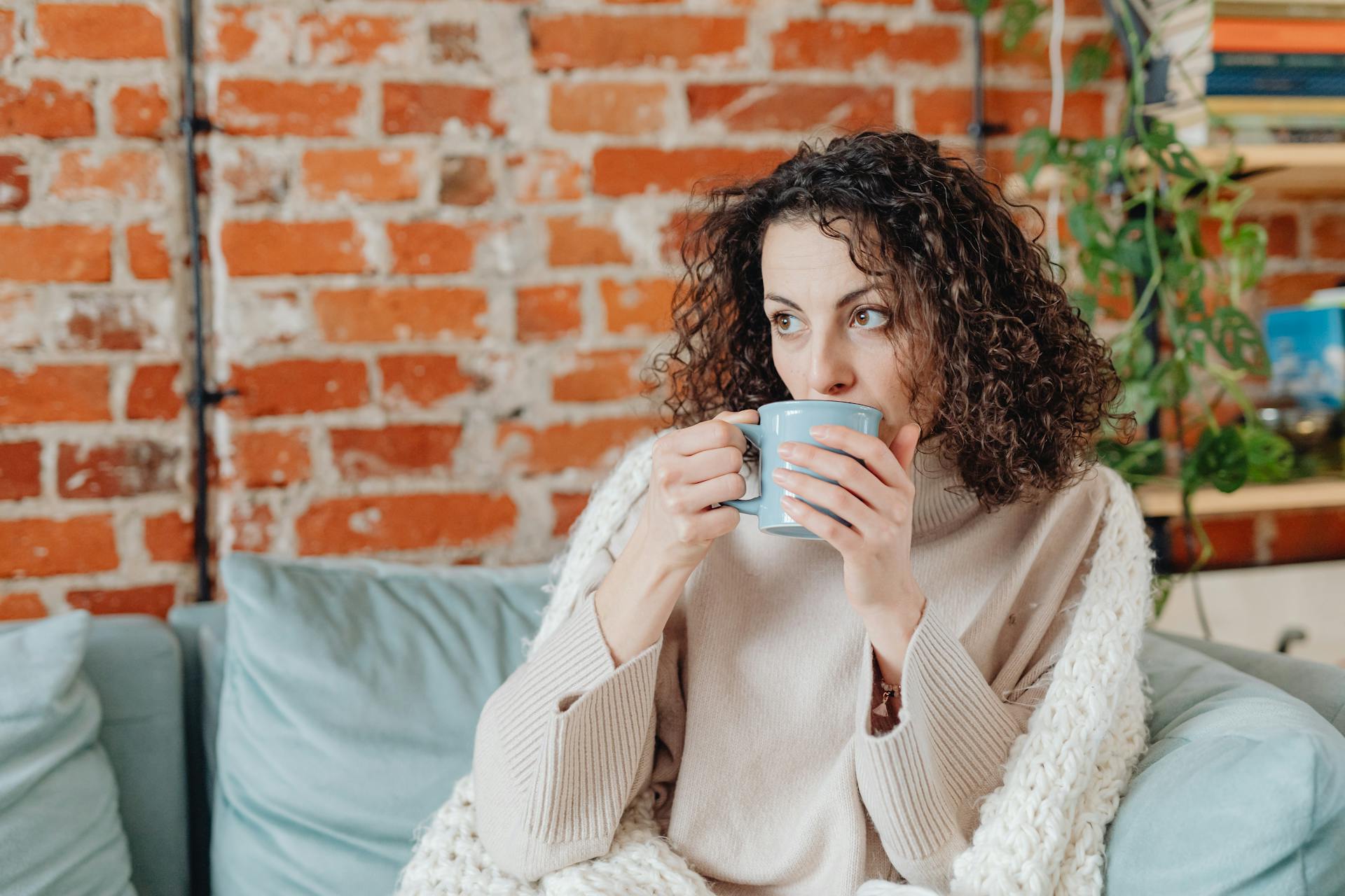 A woman drinking a warm beverage on a couch | Source: Pexels