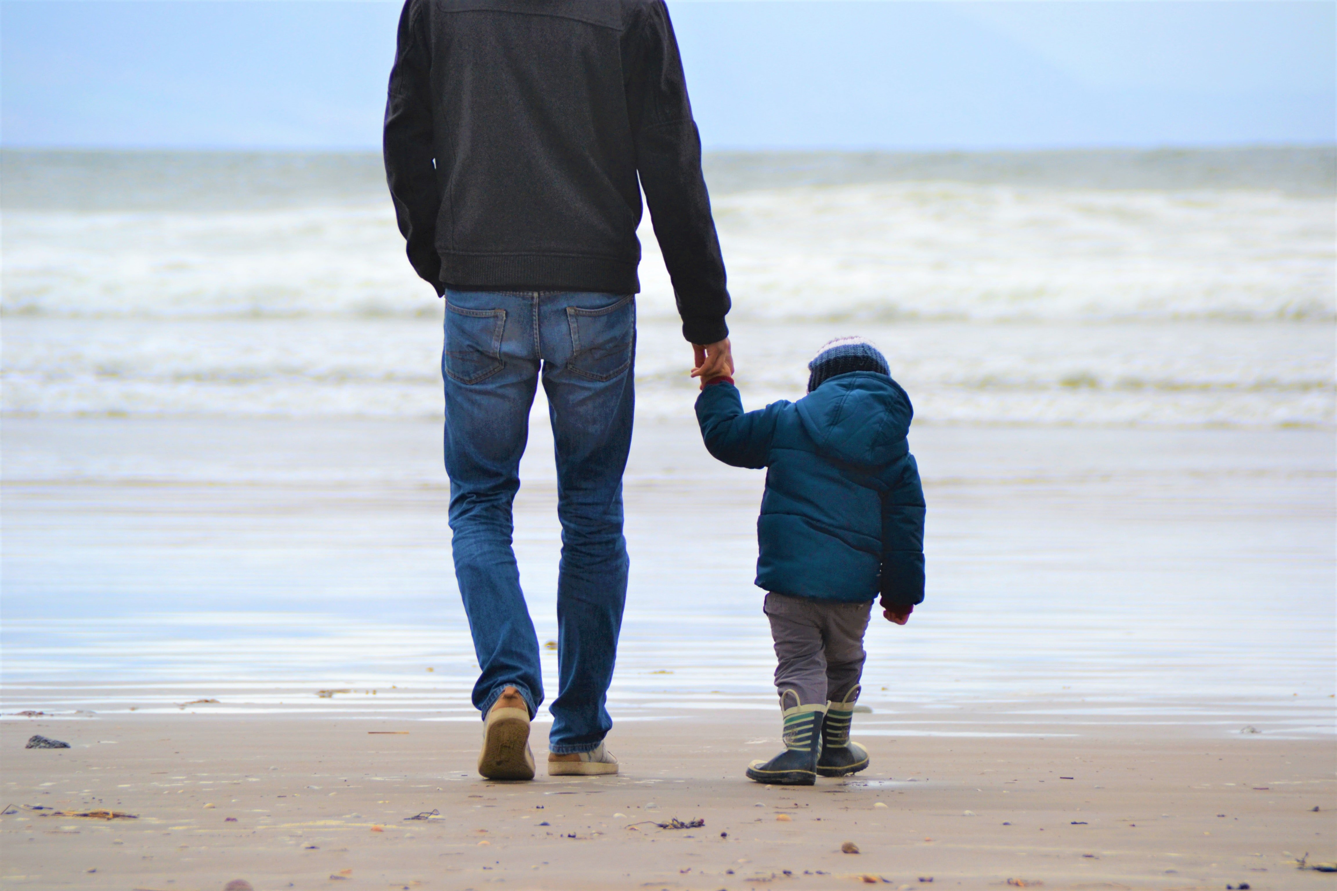 Un padre camina por la playa con su pequeño hijo. | Foto: Unsplash